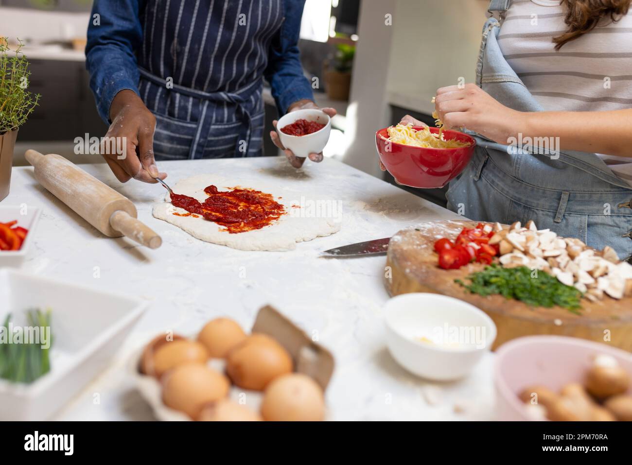 Die Mitte von verschiedenen Teenager-Freundinnen, die Pizza in der Küche machen Stockfoto