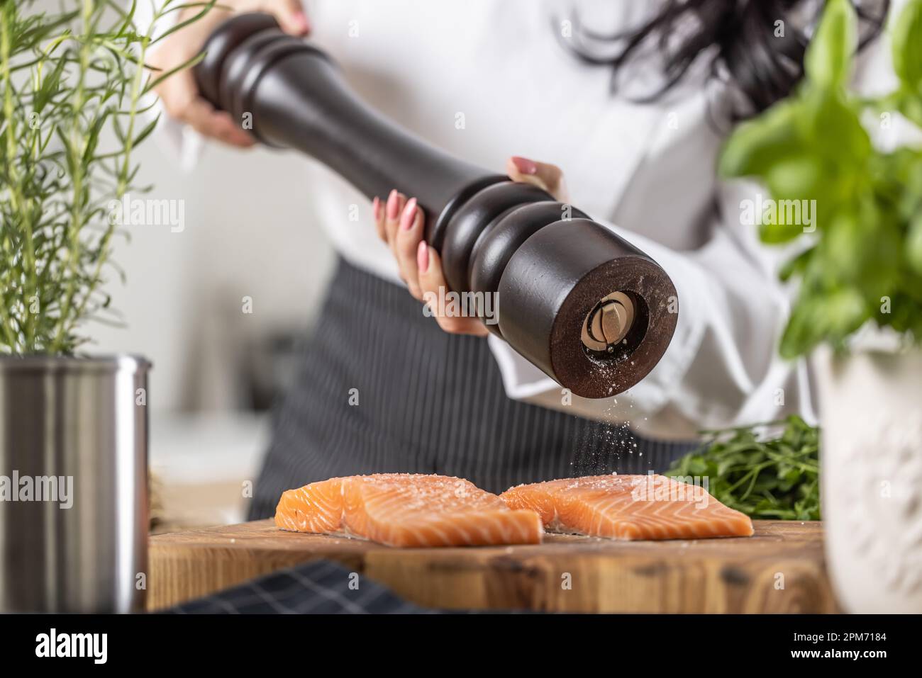 Klassischer schwarzer Holzpfeffer, der von einem Koch zum Würzen von Lachsfilets verwendet wird. Stockfoto