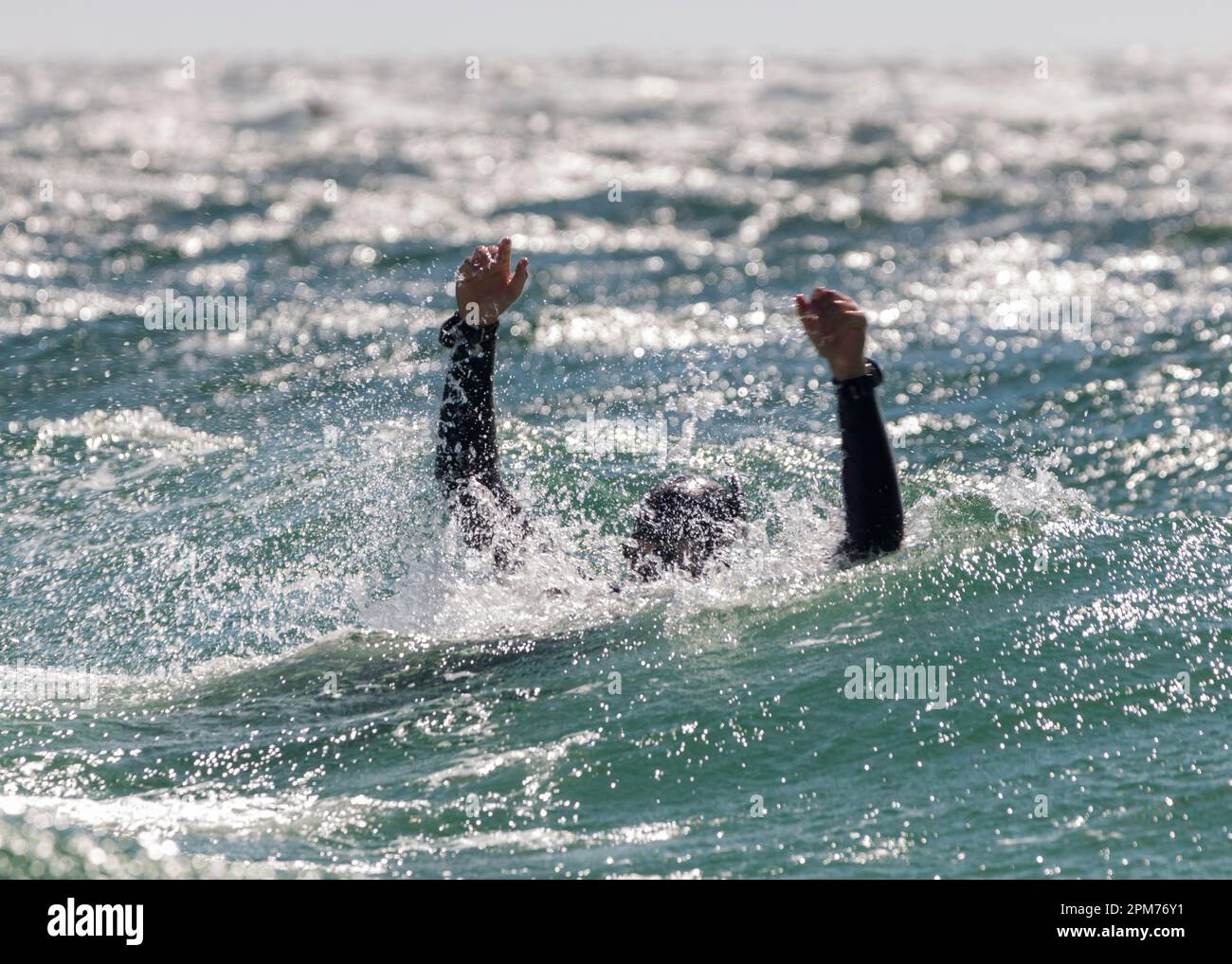 Ein Taucher in Not signalisiert im Meer mit Armen in der Luft, um Hilfe bei einer Rettungsübung für Taucher zu signalisieren Stockfoto