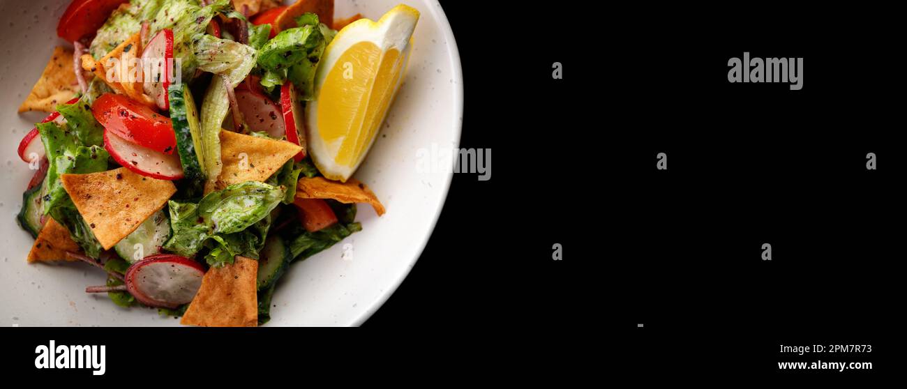 Gesunder Salat mit knusprigen Chips und frischem Gemüse auf schwarzem Hintergrund Stockfoto