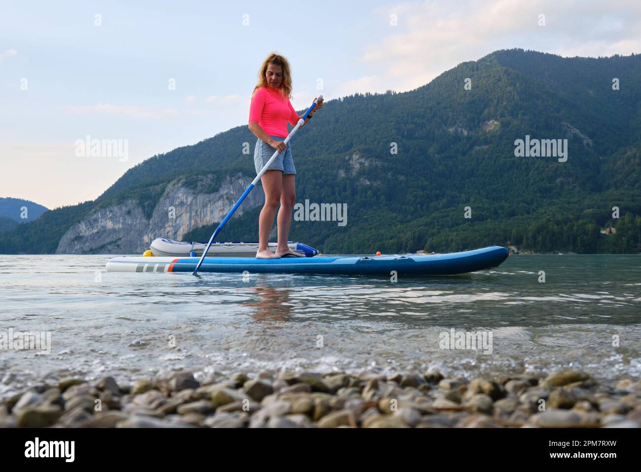 Frau auf Stand-Up-Paddle-Board (SUP) am Wolfgangsee, Österreich, in der Nähe der Küste. Aktiv, Tourismus, Sommer, Aktivität, Side. Stockfoto