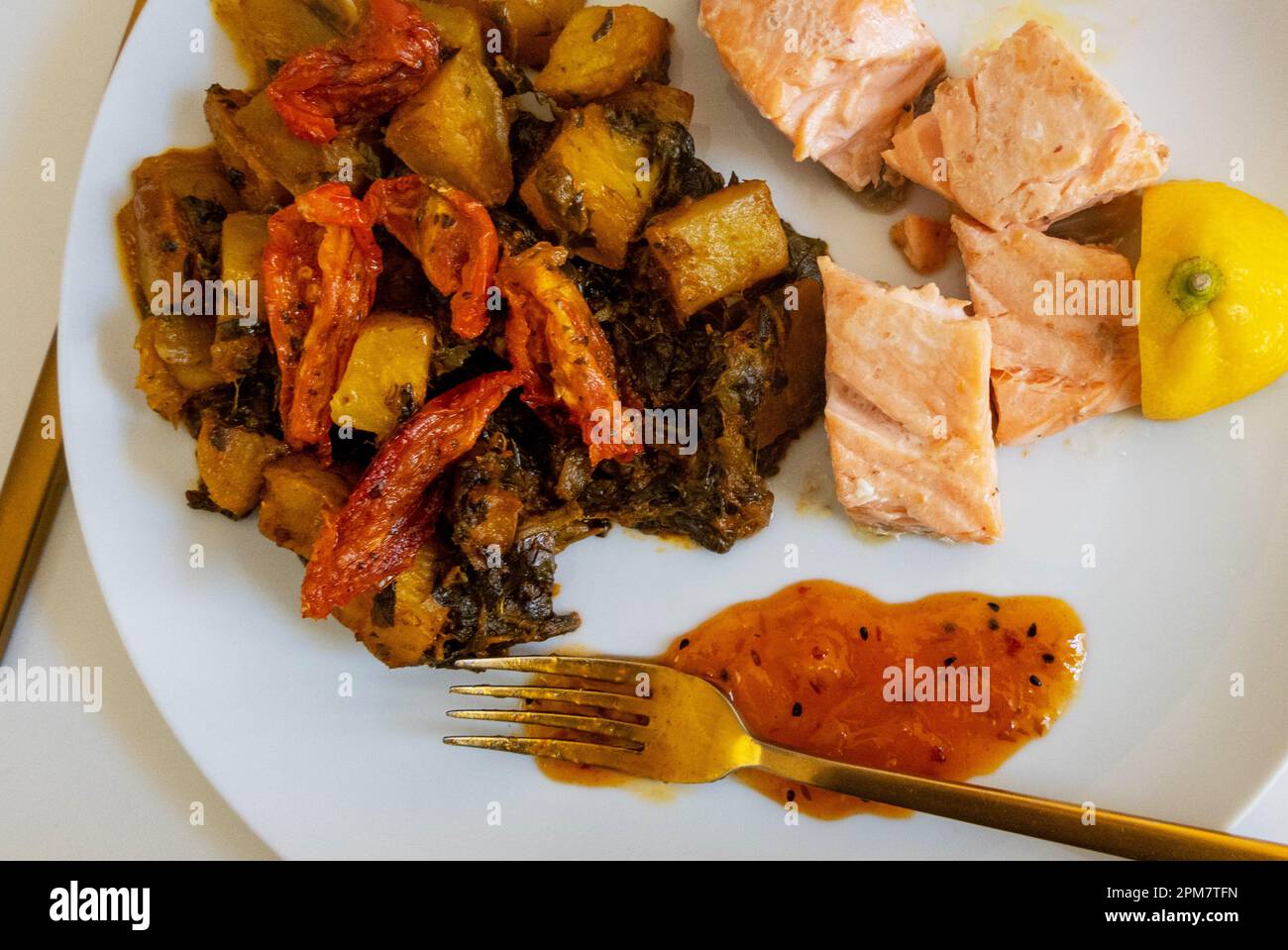 Gegrillter Lachs mit Spinat, Kartoffeln und gegrillten Tomaten mit Zitrone und Chutney Stockfoto