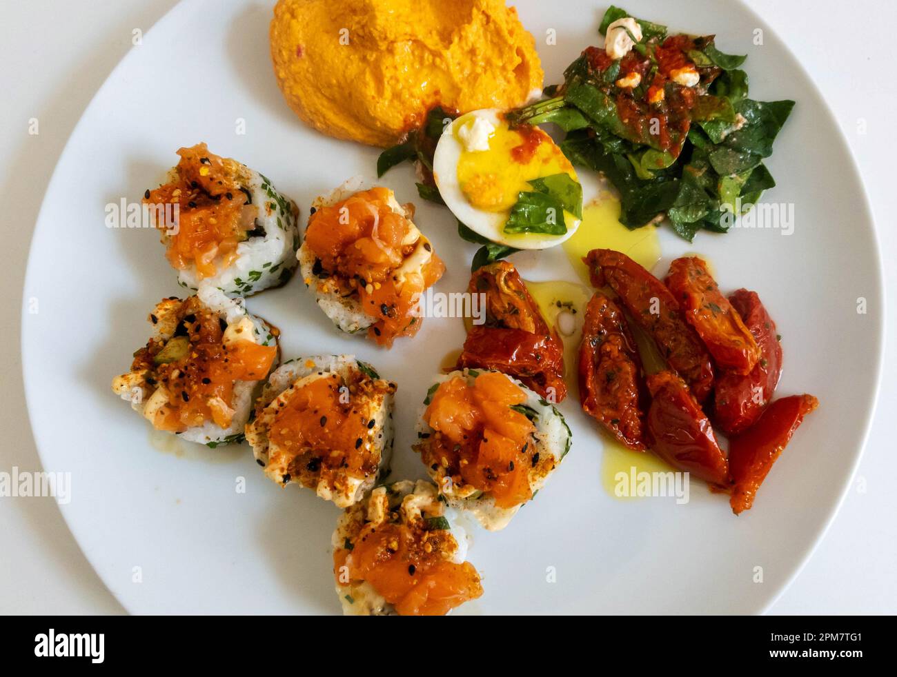 Kaltes internationales Antipasti - Sushi, Eiersalat, Hummus, gegrillte Tomaten Stockfoto