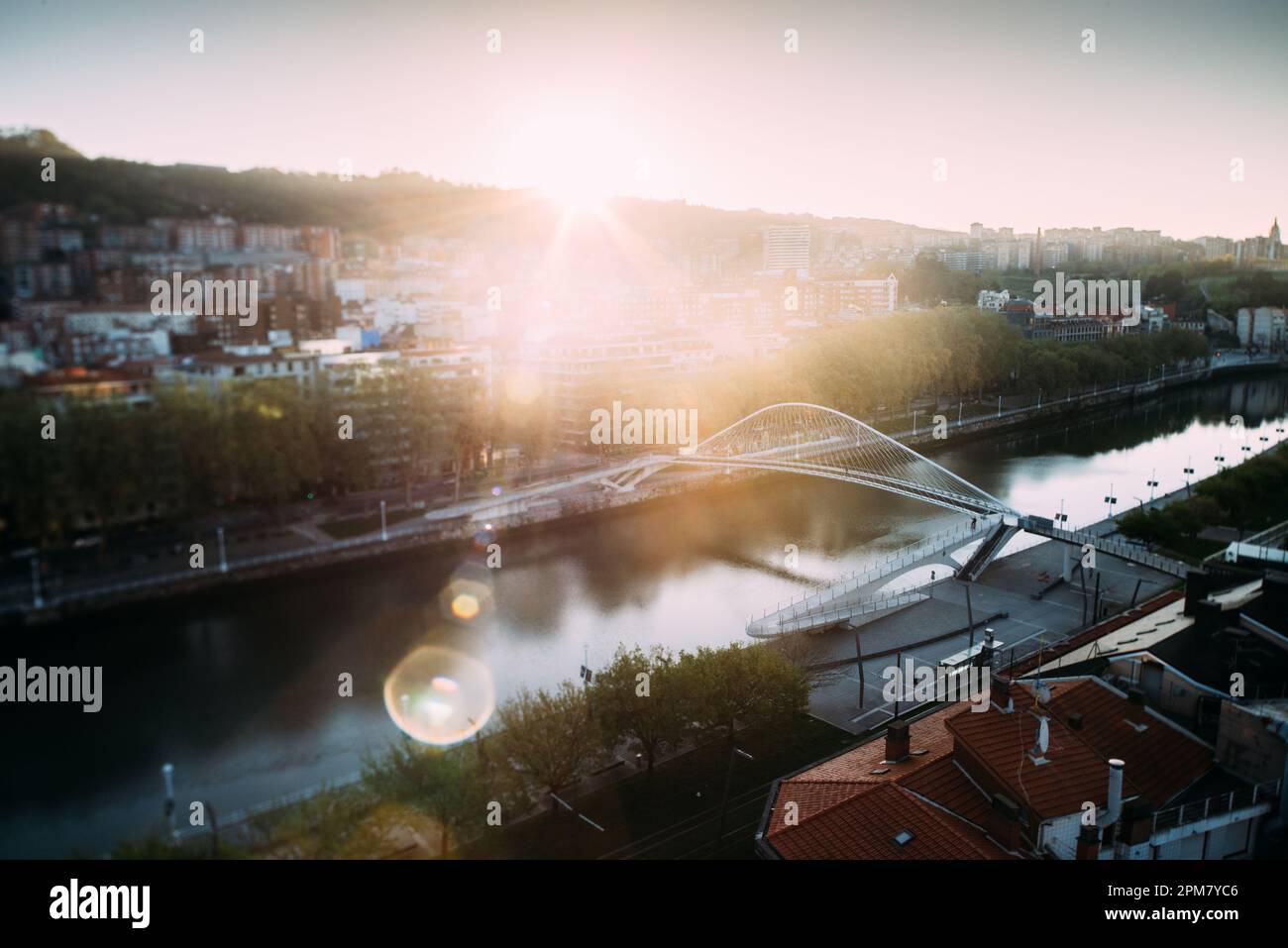 Stadtbild von Bilbao und Fußgängerbrücke Zubizuri mit Hintergrundbeleuchtung am frühen Morgen, Bilbao, Baskenland, Spanien - Neigeverschiebung mit selektivem Fokus Stockfoto