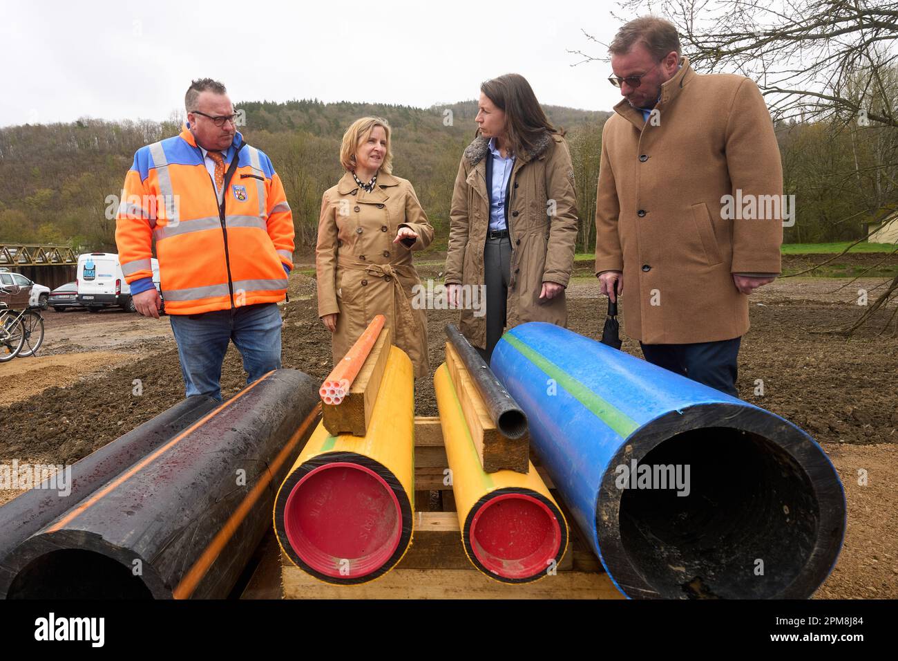 12. April 2023, Rheinland-Pfalz, Dümpelfeld: Rheinland-Pfalz Staatssekretär für Verkehr Andy Becht (FDP, l-r), Rheinland-Pfalz Ministerin für Umwelt Katrin Eder (Grüne), Cornelia Weigand (Bezirksverwalterin des Bezirks Ahrweiler, keine Parteizugehörigkeit) und Präsident der Direktion Struktur und Genehmigung Nord (SGD) Wolfgang Treis (Grün) Sehen Sie sich die Rohre an, die in einer Infrastrukturroute unter einem Radweg im Ahr-Tal verlegt sind. Die Flutkatastrophe im Ahr-Tal hatte schwere Schäden an der Wasserversorgung verursacht. Foto: Thomas Frey/dpa Stockfoto