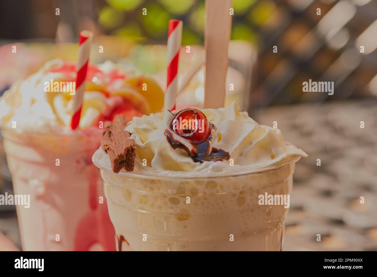 Köstliche Sommermilchshake-Getränke mit Obst, Schokolade und cremiger Sahne mit gestreiften Strohhalmen. Stockfoto