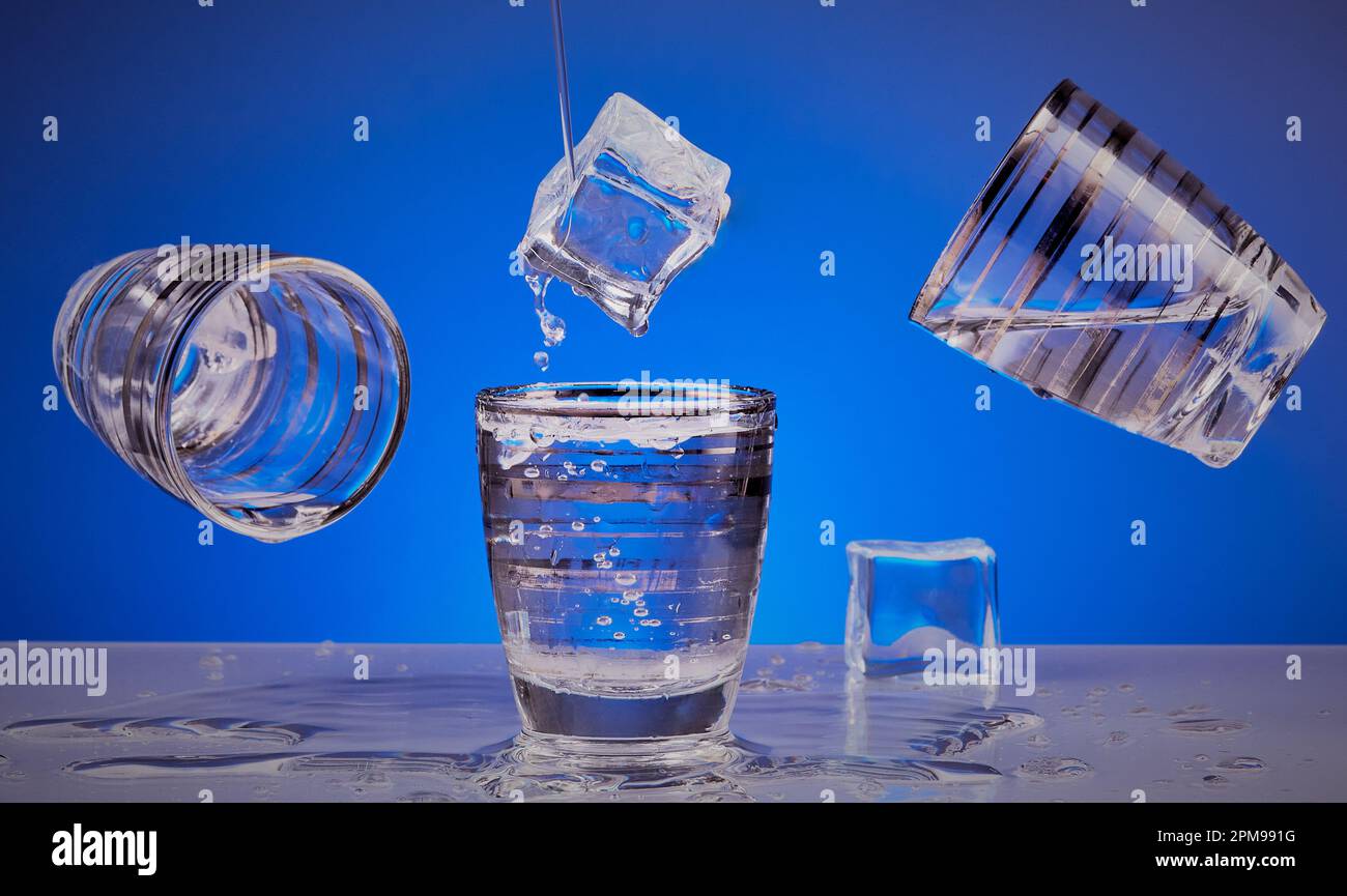 Wodka-Shot-Gläser mit Eiswürfeln mit blauem Hintergrund. Stockfoto