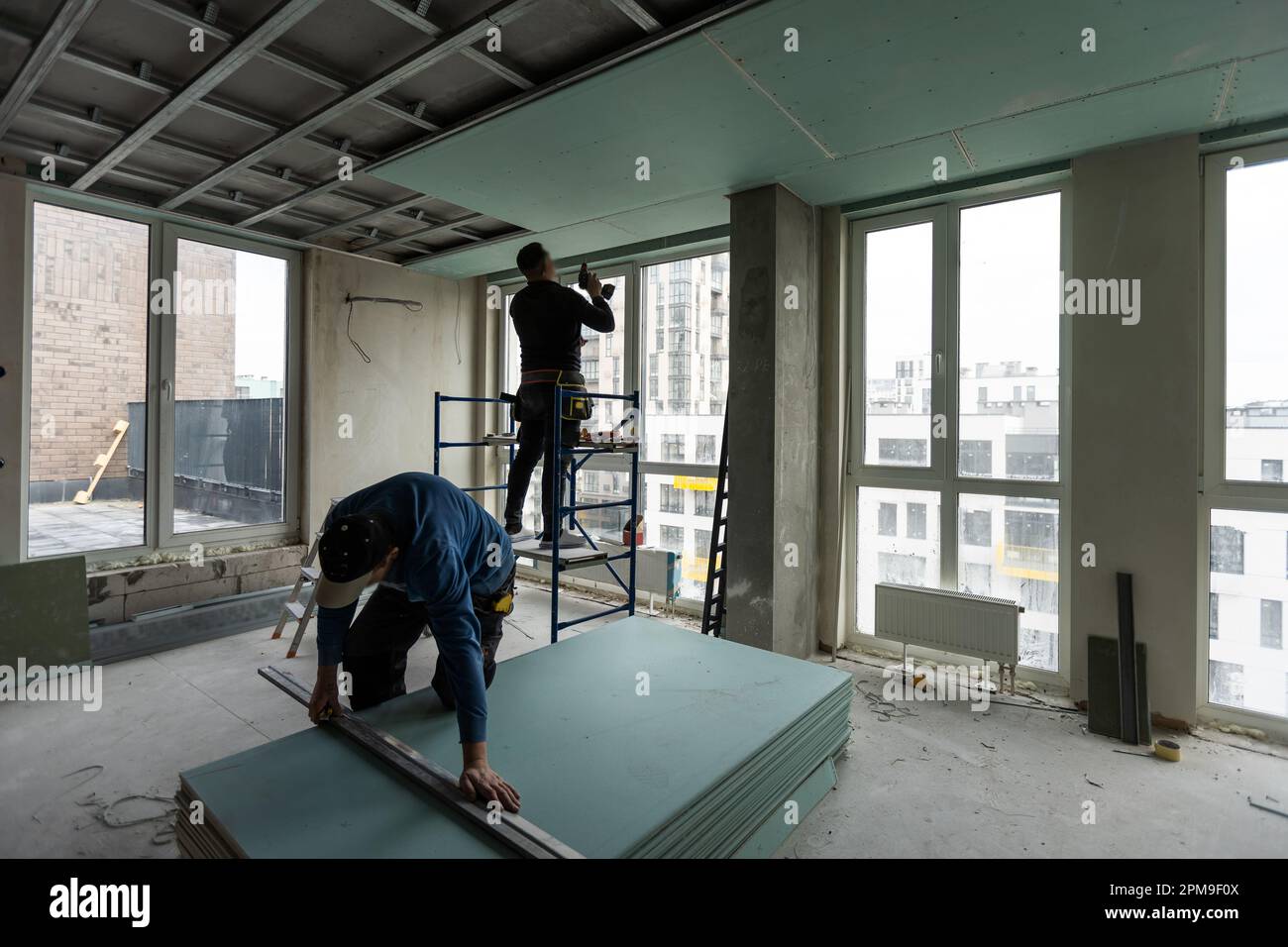 Deckenmontage mit fachkundigen Technikern in dem Raum, der sich im Bauprozess befindet Stockfoto