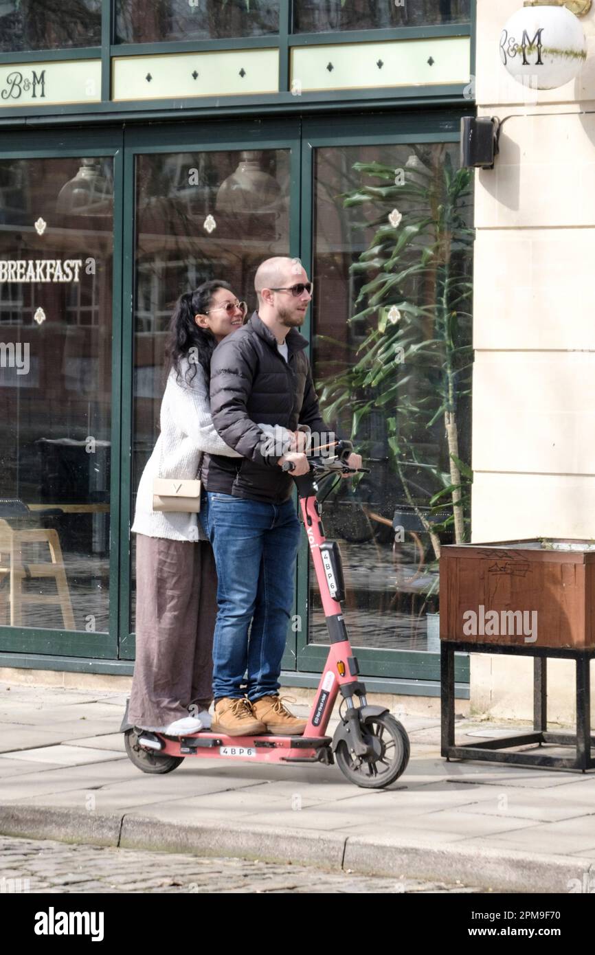 Ein Mann und eine Frau, zwei Personen, die einen VOI E-Scooter fahren, der für einen in Bristol UK gemacht wurde Stockfoto