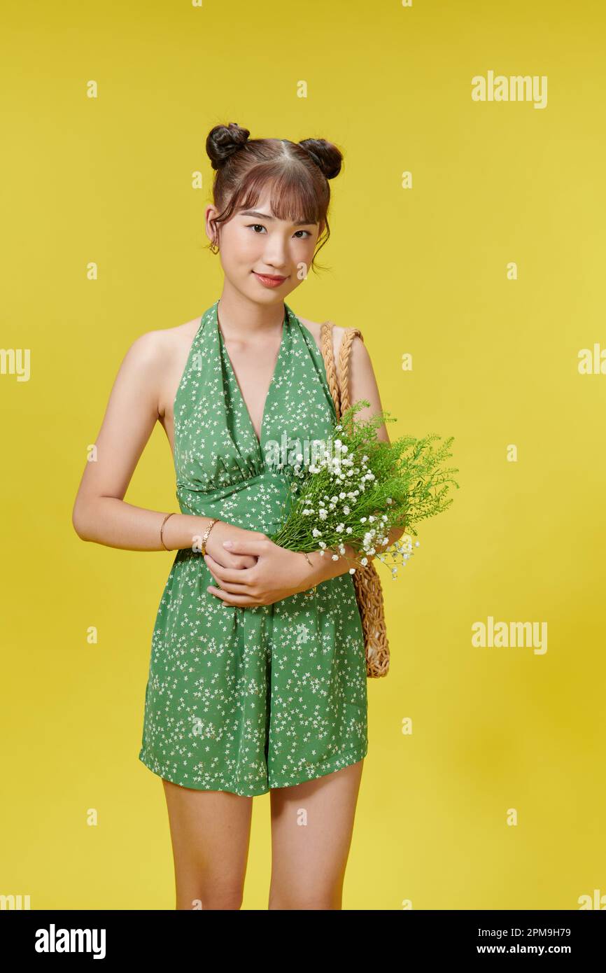 Foto einer netten jungen asiatischen Dame mit Blumenstrauß Tragen Sie Sommerkleidung isoliert auf gelbem Hintergrund Stockfoto