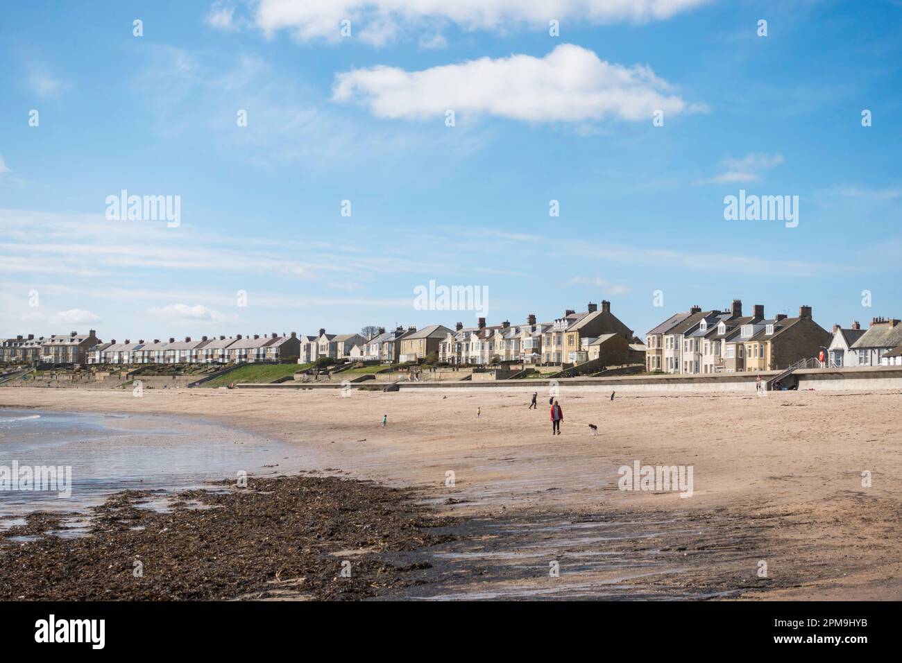 Leute, die am Strand in Newbiggin by the Sea, Northumberland, England, Großbritannien spazieren gehen Stockfoto