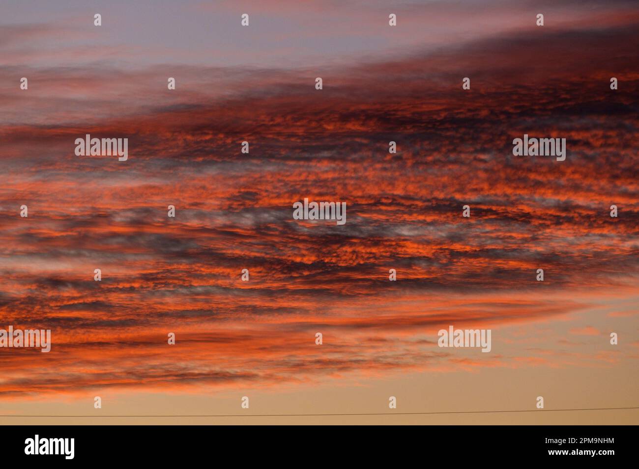 Sonnenuntergang im Herbst, der tiefe Farbe in den Wolken erzeugt, während die Sonne unter den Horizont taucht. Stockfoto