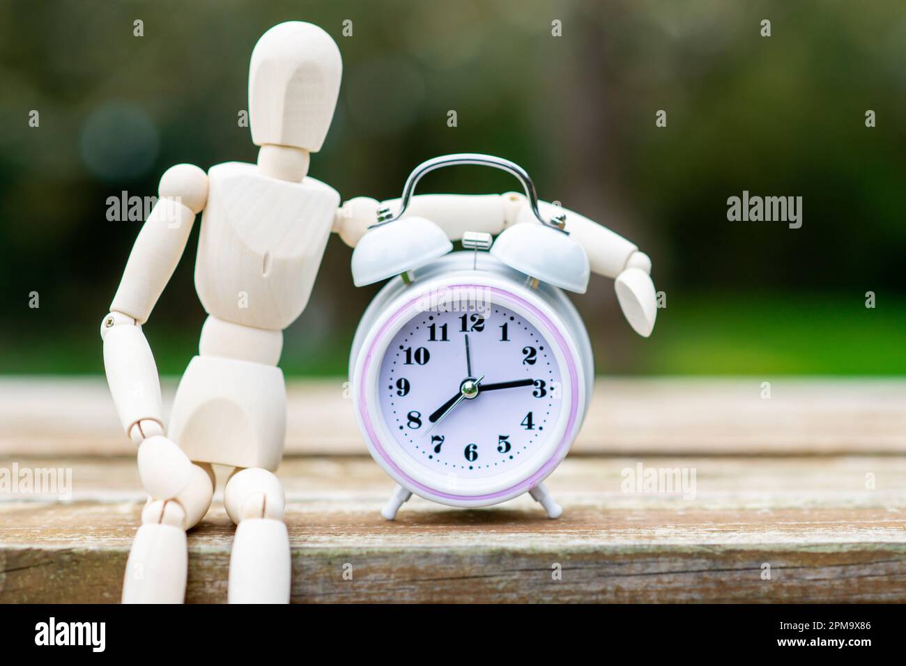 Eine Figur von einem Mann und einem Wecker. Das Konzept der Zeit, des zirkadianen Rhythmus, der Deadline. Stockfoto
