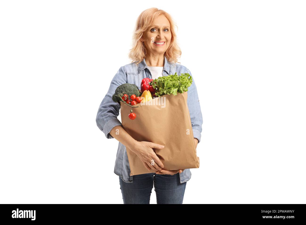 Reife Frau, die eine Papiertüte mit Lebensmitteln auf weißem Hintergrund trägt Stockfoto