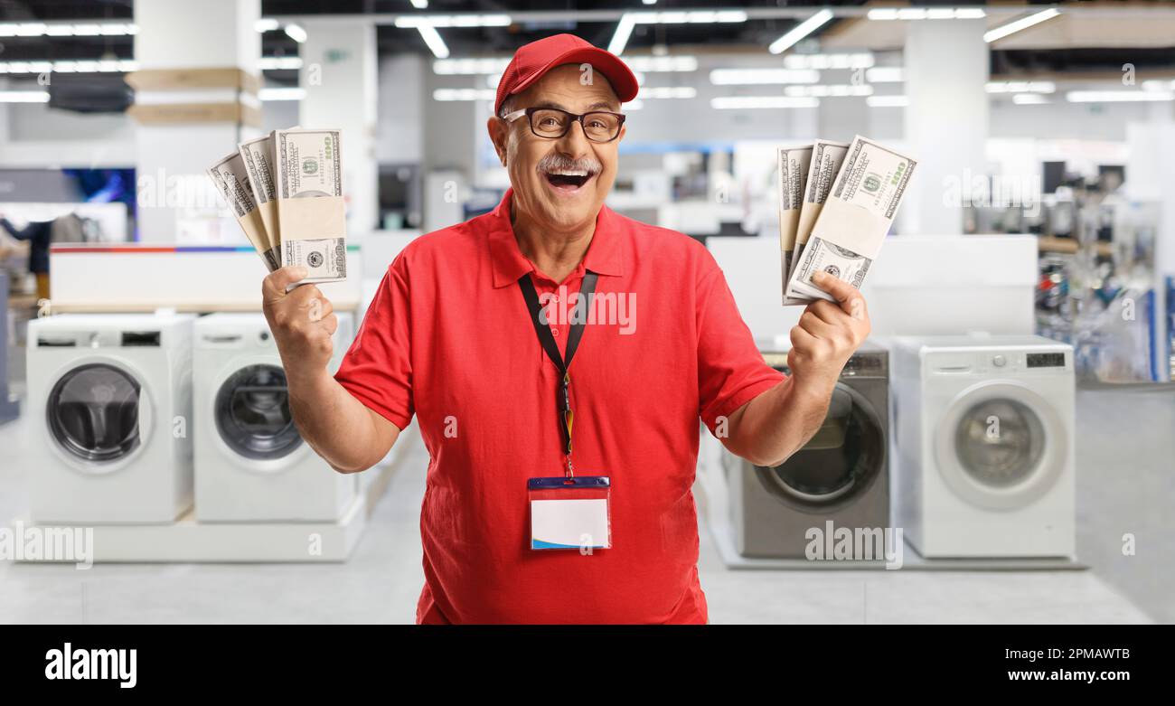 Ein erfahrener Store Manager, der Geld in der Hand hat und in einem Geschäft für Elektrogeräte lächelt Stockfoto