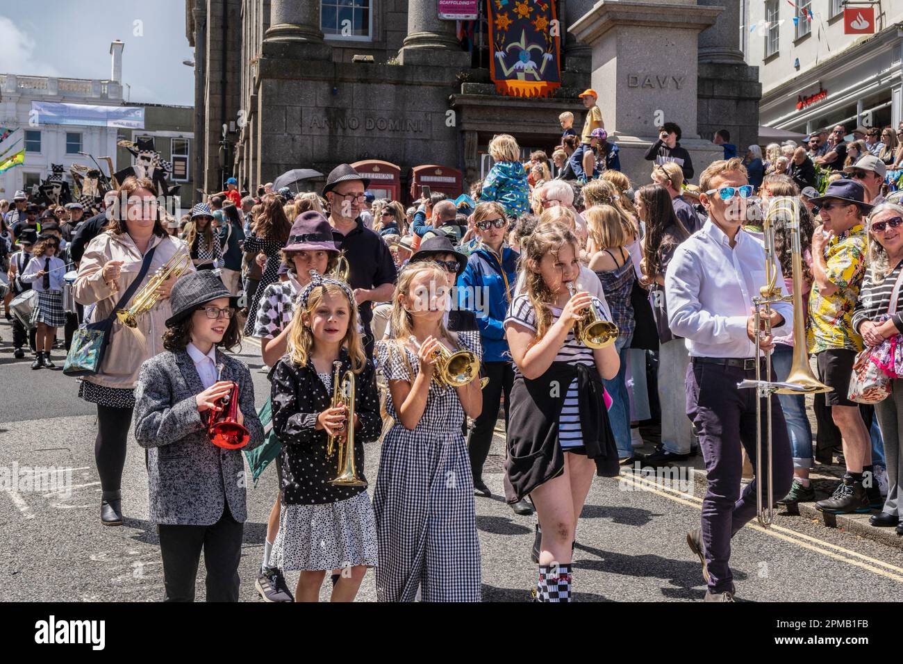 Schulkinder, die bei der Parade zum Mazey Day im Rahmen des Golowan Festivals in Penzance in Cornwall im Vereinigten Königreich Instrumente spielen. Stockfoto