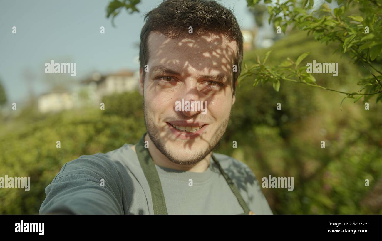 Ein junger gutaussehender Bauer oder Gärtner mit braunem Haar, der eine Videokonferenz auf seinem Telefon führt - pov Shot Stockfoto