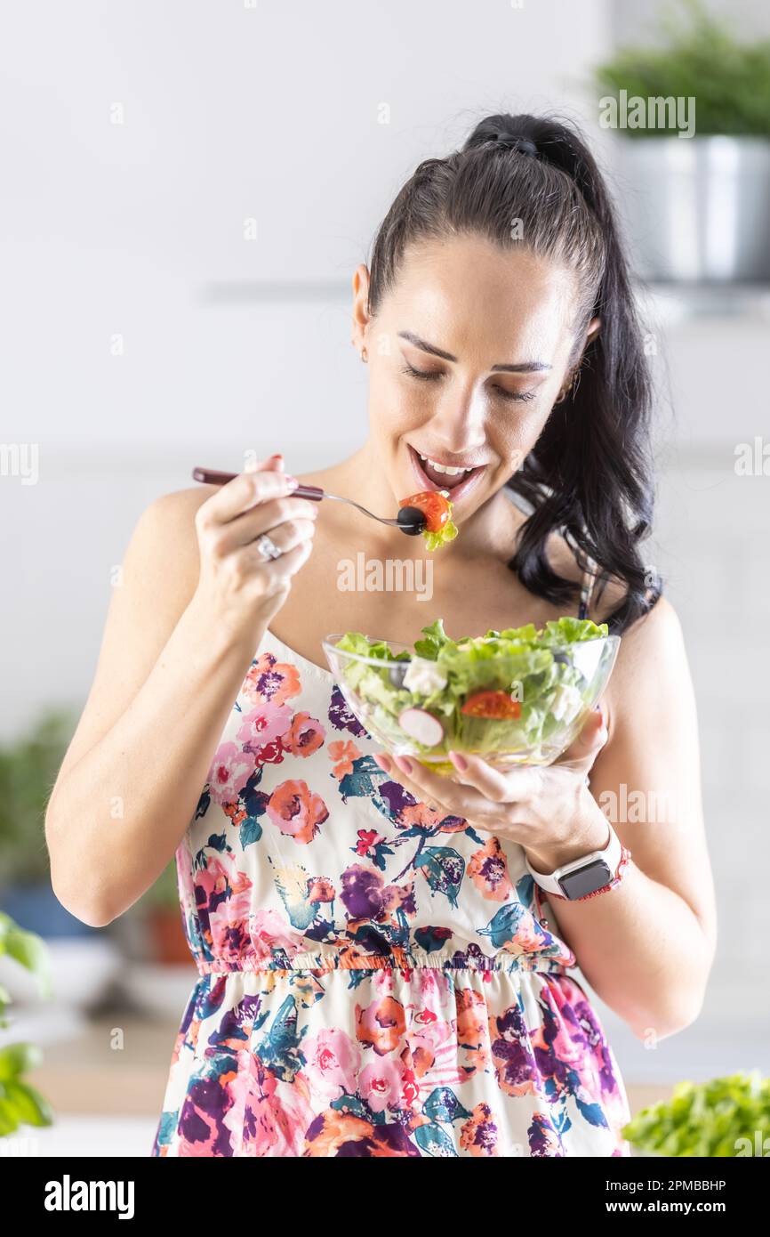 Eine junge Frau hat einen gesunden Salat zum Frühstück und steht in ihrer Küche. Stockfoto