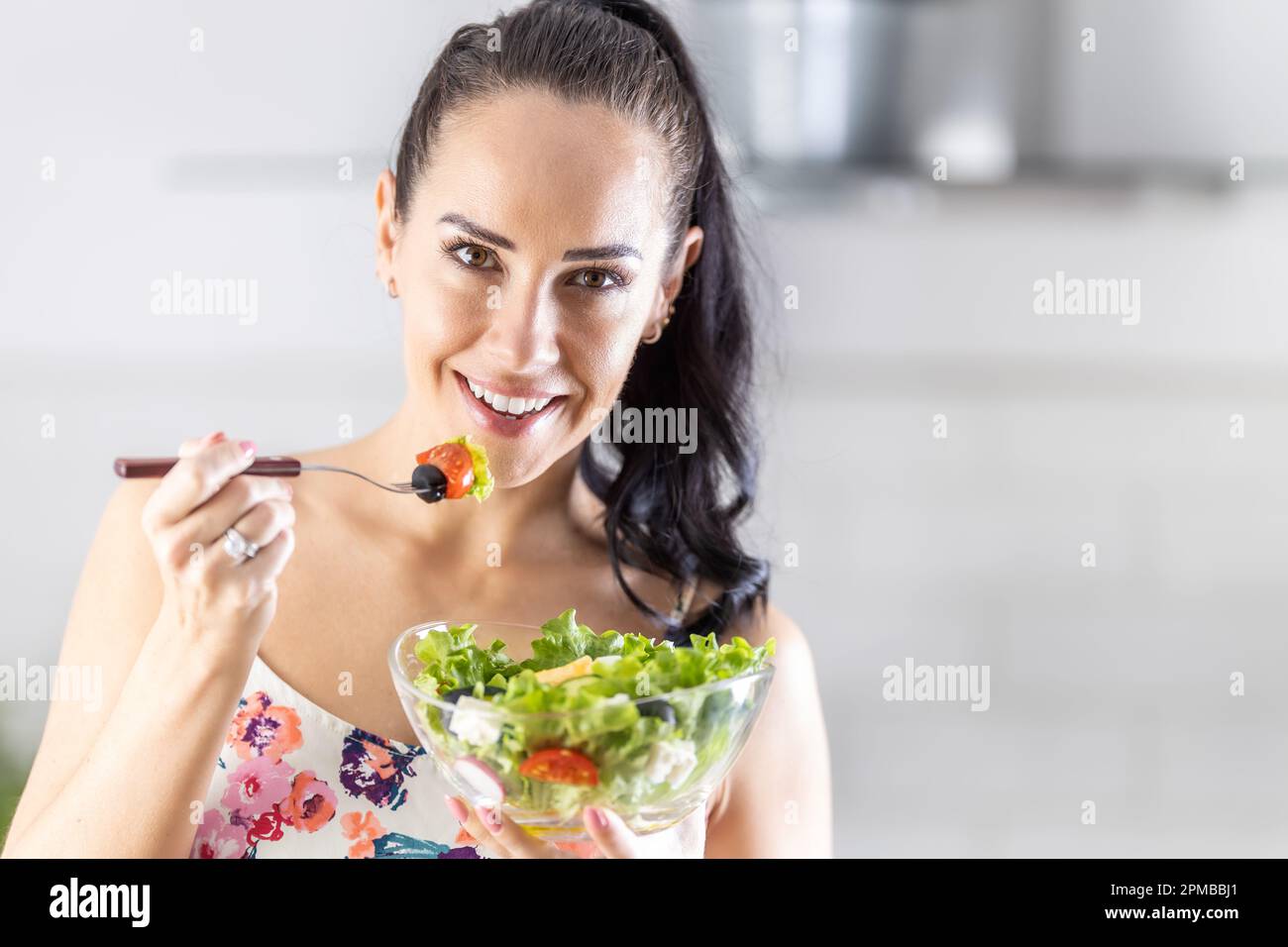 Gesunde Lebensweise junge Frau isst Salat. Junge Brünette, die in ihrer Küche gesundes Essen isst. Stockfoto