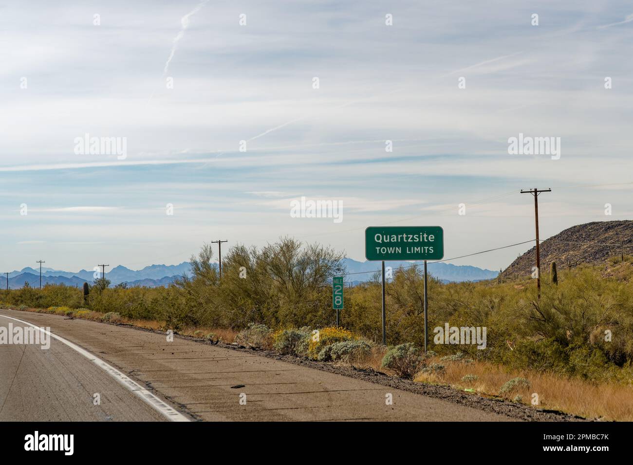 Am Straßenrand in Quartzsite, Arizona, befindet sich ein Schild mit weicher Bergregion in der Ferne. Quartzsite war einmal eine Stage-Statistik Stockfoto
