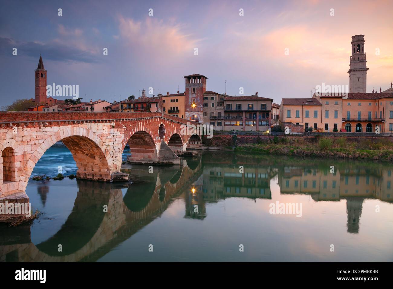 Verona, Italien. Stadtbild der wunderschönen italienischen Stadt Verona mit Steinbrücke über dem Fluss Adige bei Sonnenuntergang. Stockfoto