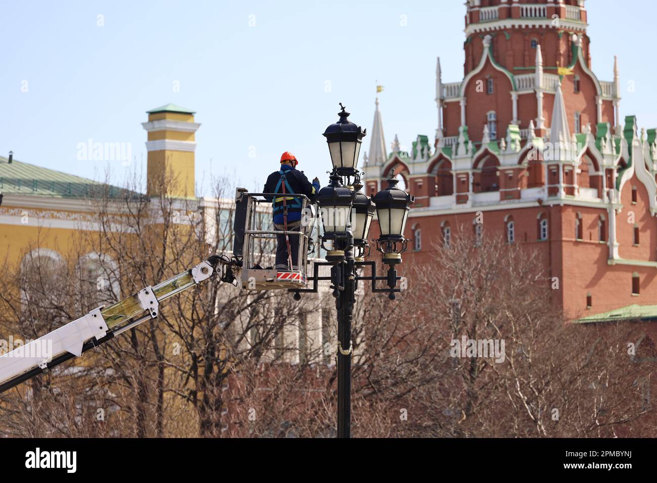 Elektriker repariert die Straßenbeleuchtung im Moskauer Kreml-Turm-Hintergrund. Arbeiter auf der Hebebühne in der Nähe der Laterne Stockfoto