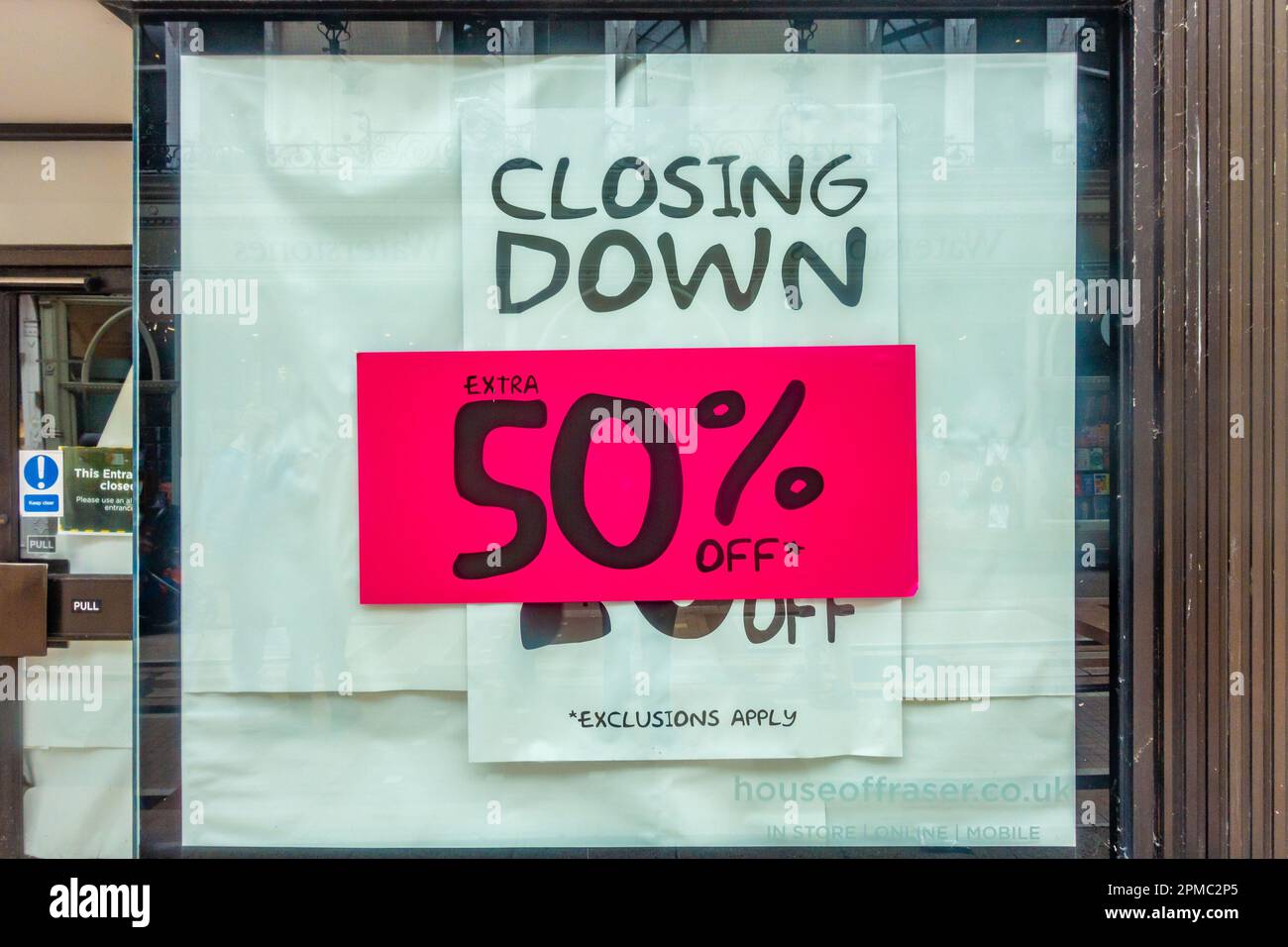 Ein Poster in einem Schaufenster, auf dem 50 % Rabatt angeboten werden, während der Laden schließt. Stockfoto