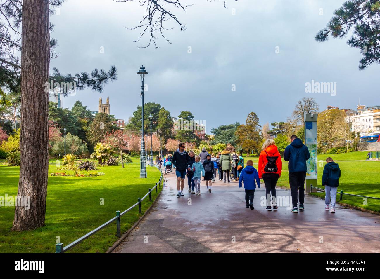 Menschen gehen durch Lower Gardens, einen öffentlichen Park und Grünflächen in Bournemouth, Dorset, Großbritannien, unter einem grauen, bewölkten, stürmischen Himmel Stockfoto