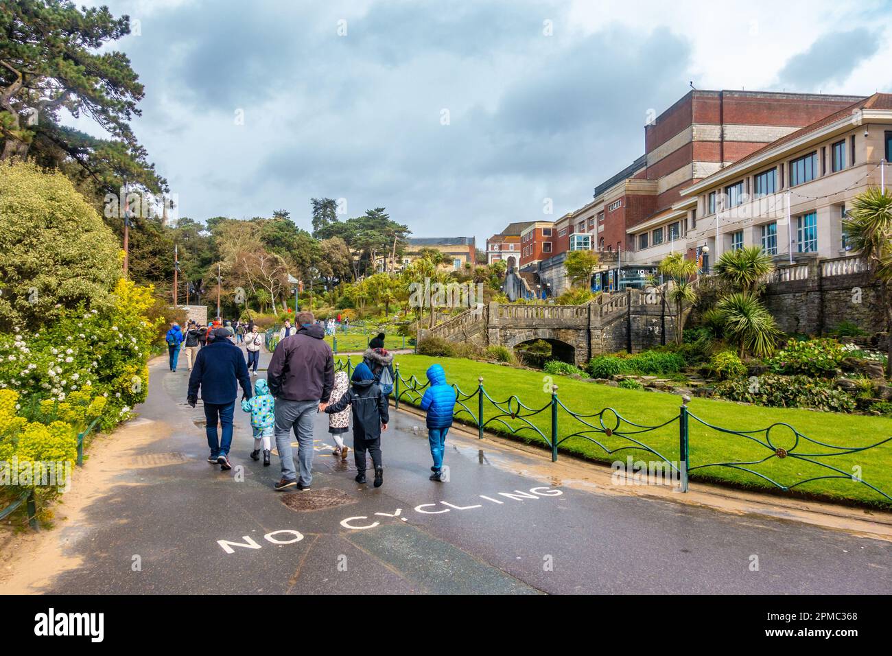 Menschen gehen durch Lower Gardens, einen öffentlichen Park und Grünflächen in Bournemouth, Dorset, Großbritannien, unter einem grauen, bewölkten, stürmischen Himmel Stockfoto