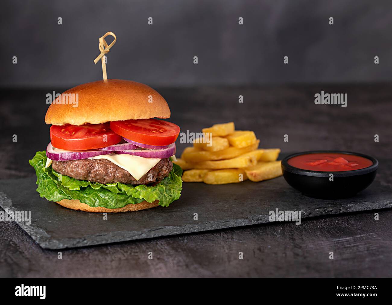 Lebensmittelfotografie mit Cheeseburger, Burger, Hamburger, Sauce, Käse, Pommes Frites, Salat, Zwiebeln, Tomaten Stockfoto