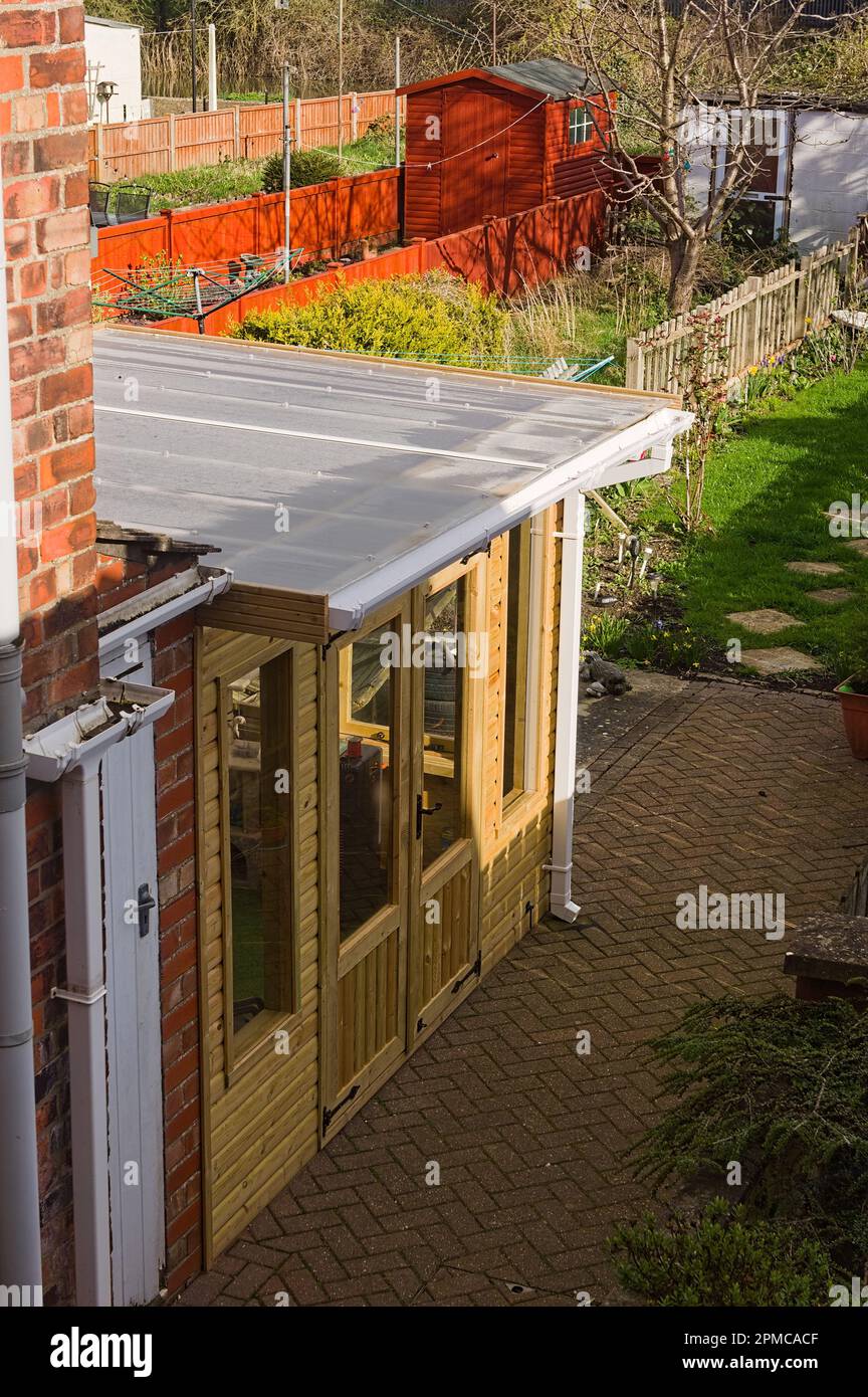 Moderner Wintergarten mit Flachdach neben einem Haus mit Gärten im Hintergrund Stockfoto