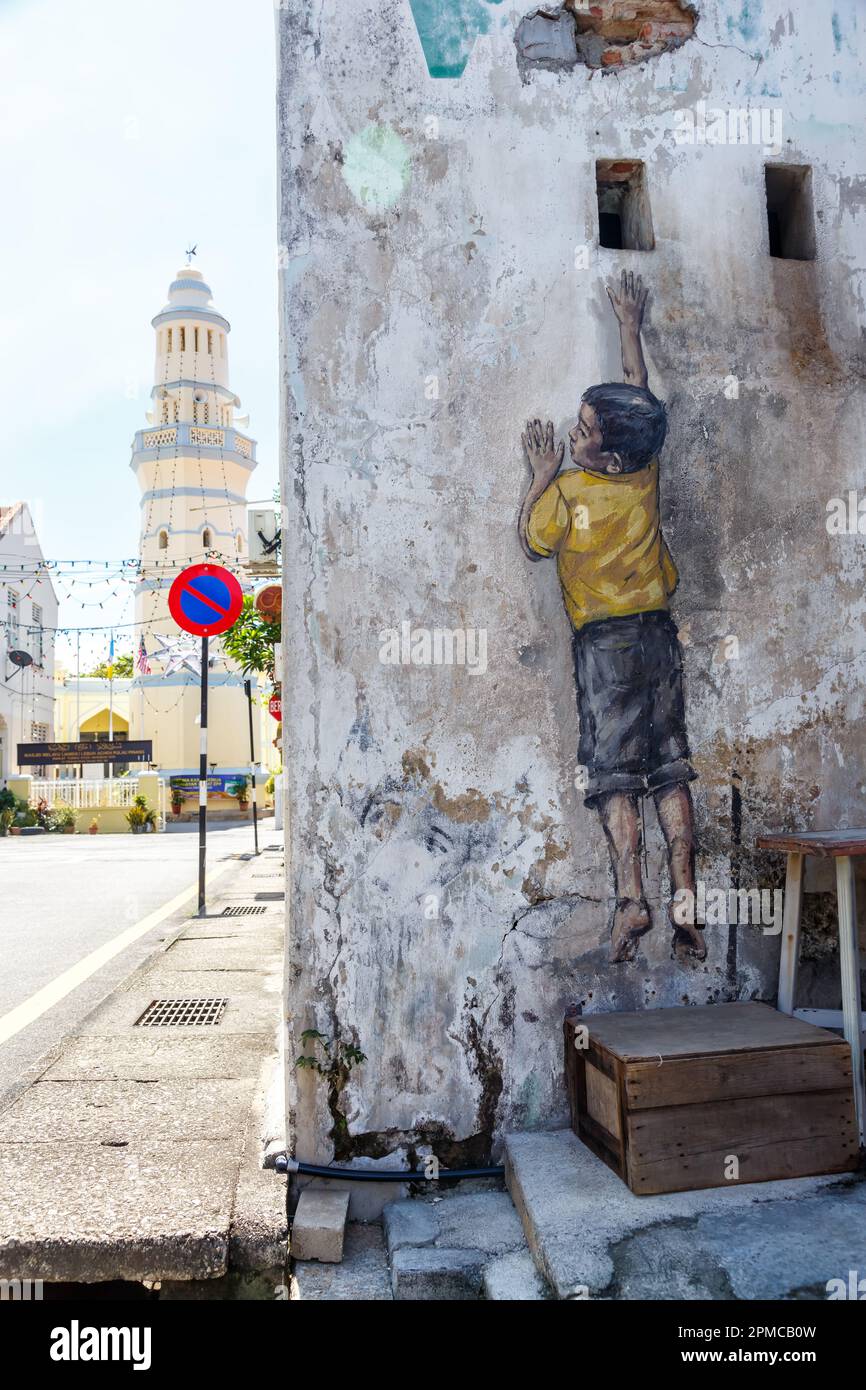 Street-Art-Wandjunge, der in George Town auf Penang Island in Malaysia ein Wandporträt aufnimmt Stockfoto