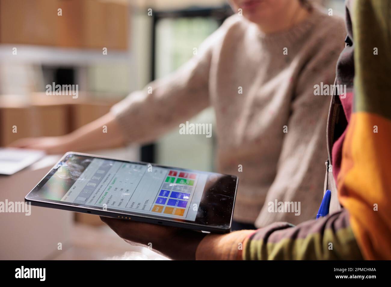 Lagerarbeiter analysieren Online-Kundenbestellungen auf digitalen Geräten und bereiten Pakete für den Versand vor. Vielfältige Mitarbeiter, die in der Warenlogistik im Lager arbeiten. Nahaufnahme Stockfoto