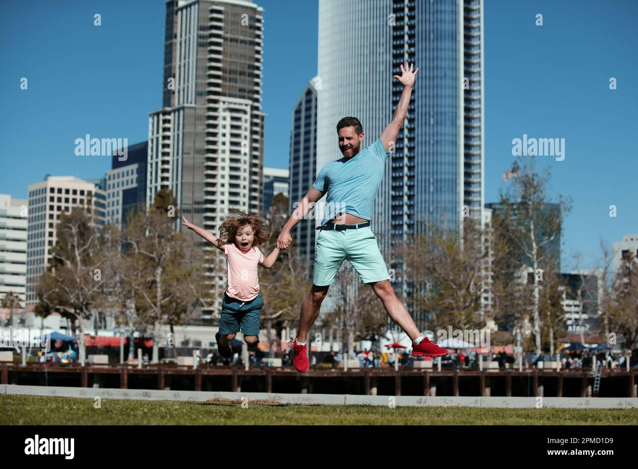 Lustige Vater und Sohn springen in der Stadt Hintergrund. Kinder-Konzept für Kindheit und Elternschaft. Glücklicher Vater und Sohn spielen gemeinsam im Freien. Stadtfamilien. Stockfoto