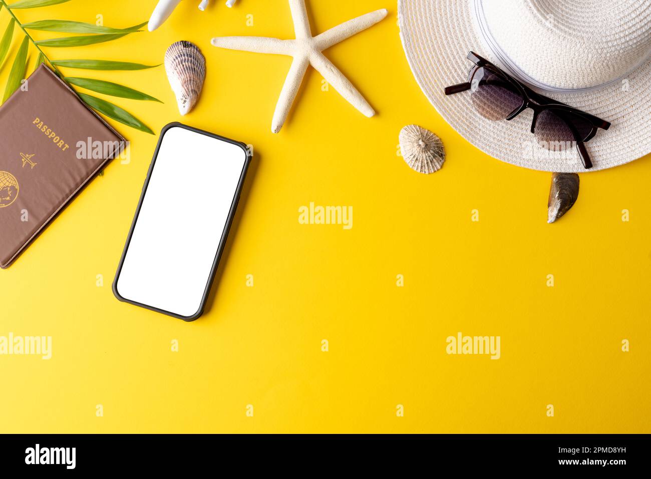 Smartphone mit Kopierbereich auf dem Bildschirm, Flugzeugmodell, Pass, Strohhut auf gelbem Hintergrund Stockfoto