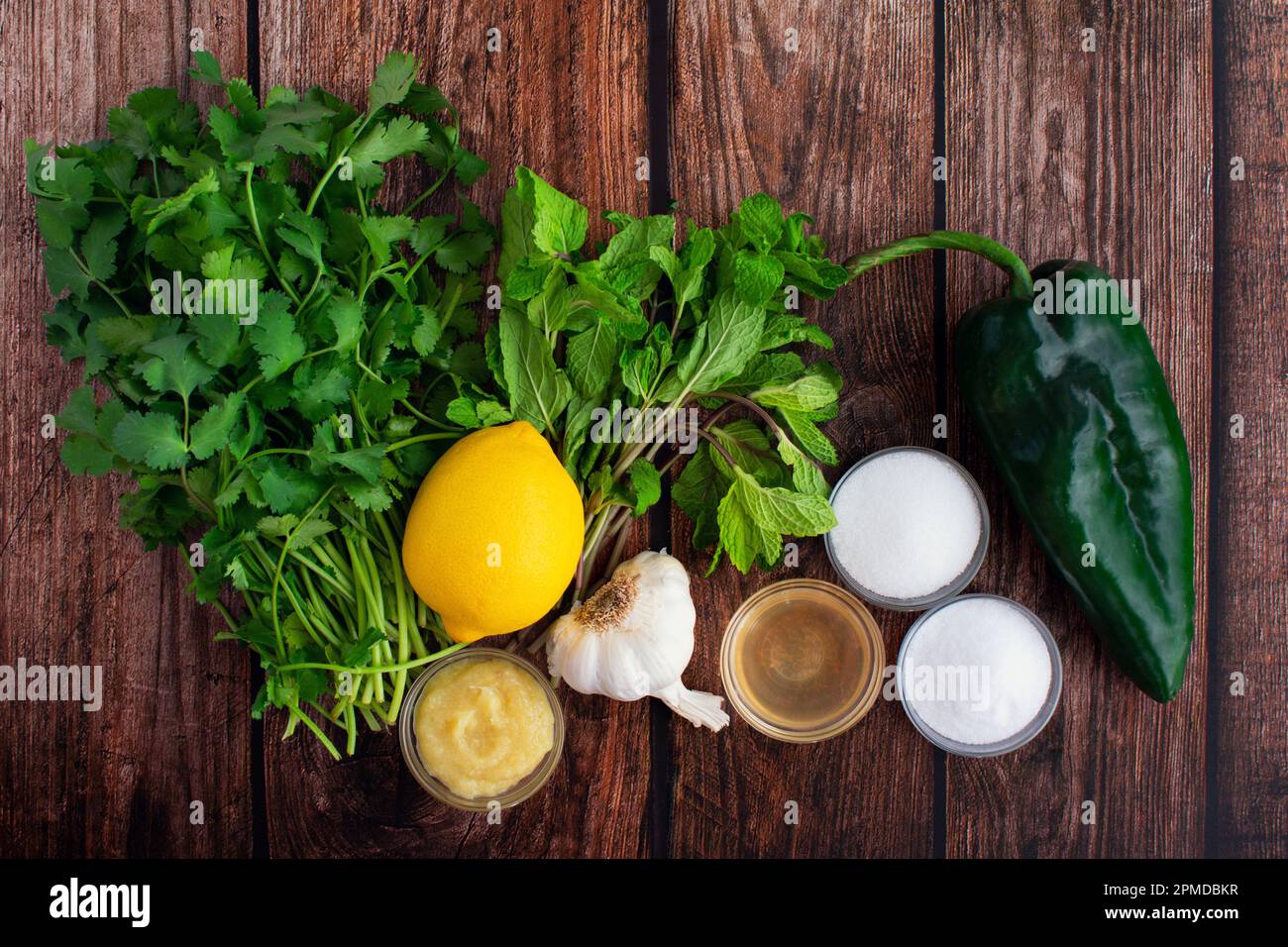 Cilantro-Mint Chutney Zutaten auf einem rustikalen Holztisch: Frische Kräuter, Chili-Pfeffer und andere Zutaten für Cilantro-Minz-Chutney Stockfoto