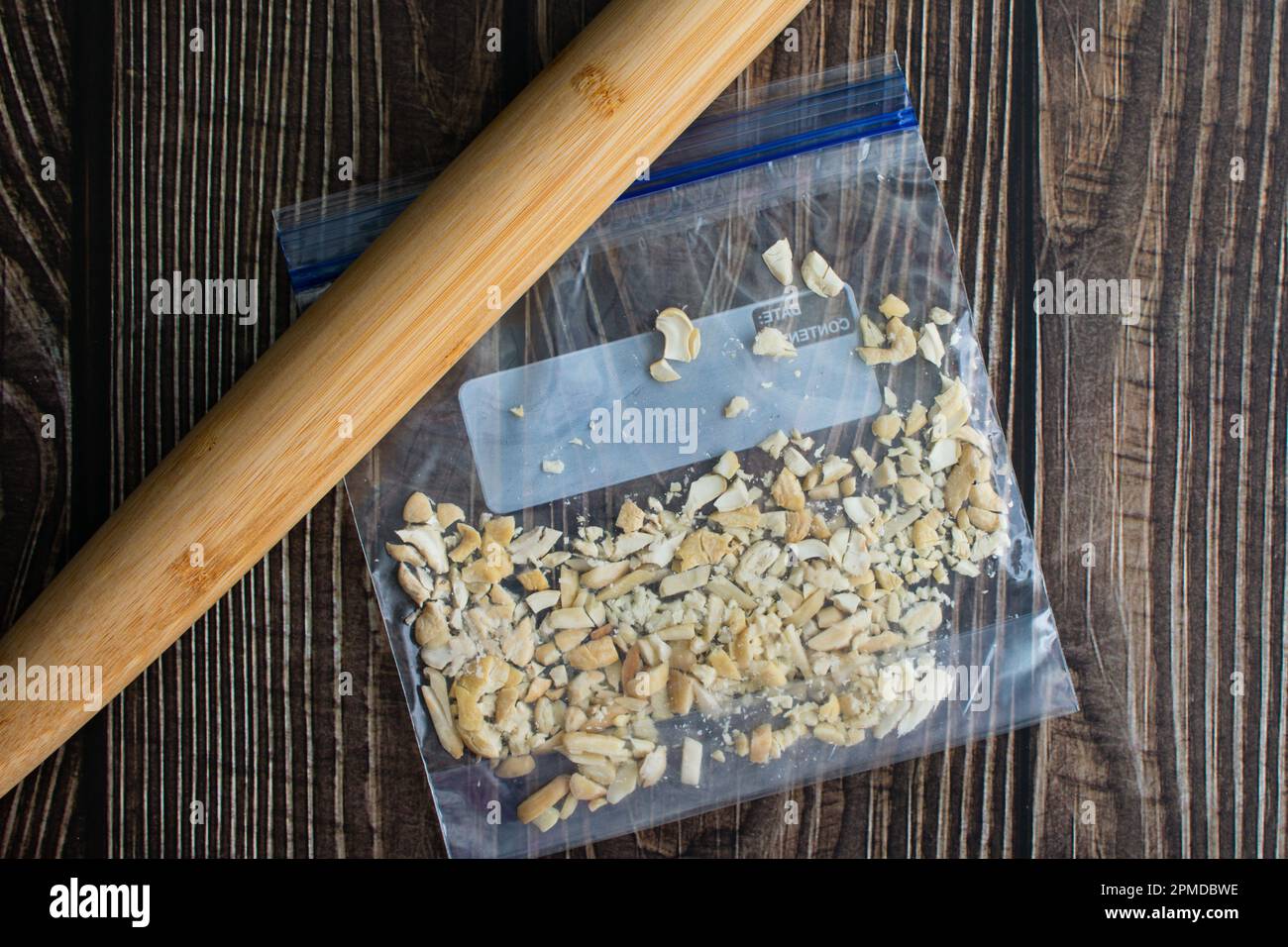 Cashews in einer Plastiktüte, die mit einem französischen Rollstift zerdrückt wurden: Muttern, die mit einem Bambus-Holzrollstift zerdrückt wurden Stockfoto