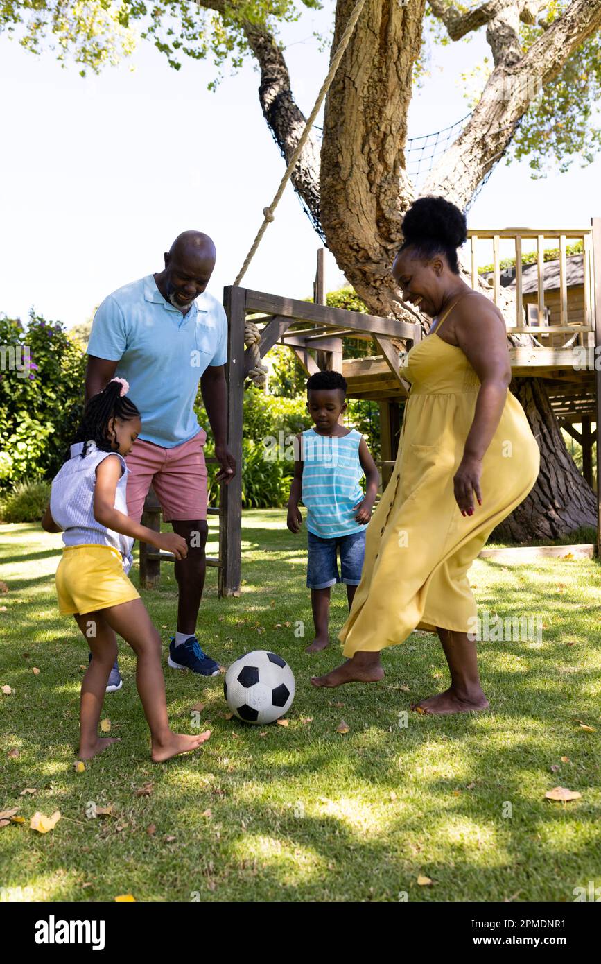 afroamerikanische fröhliche Großeltern, die mit Enkeln Fußball spielen im Park Stockfoto