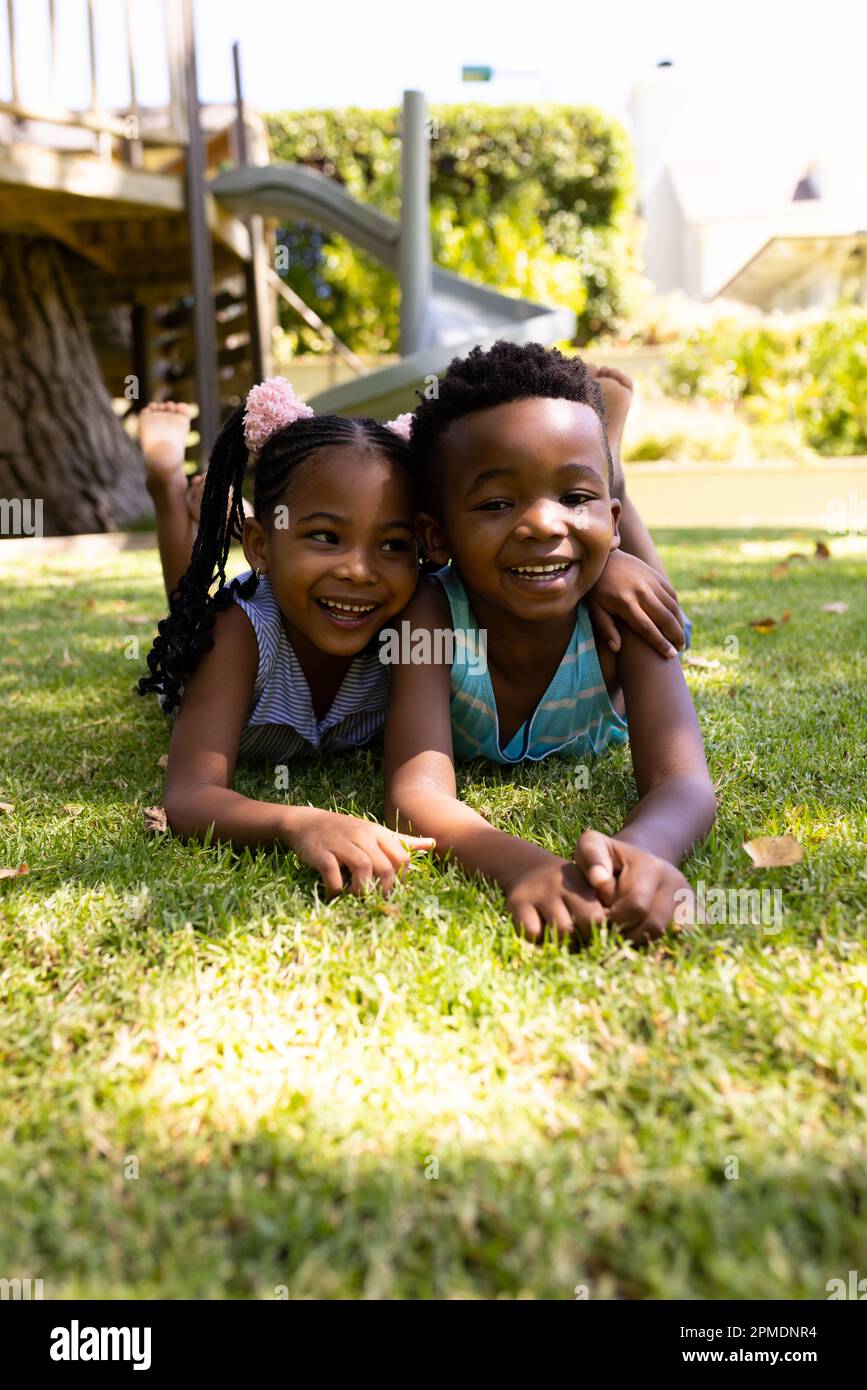 Porträt süßer afroamerikanischer Geschwister, die auf einem grasbedeckten Feld im Park liegen Stockfoto