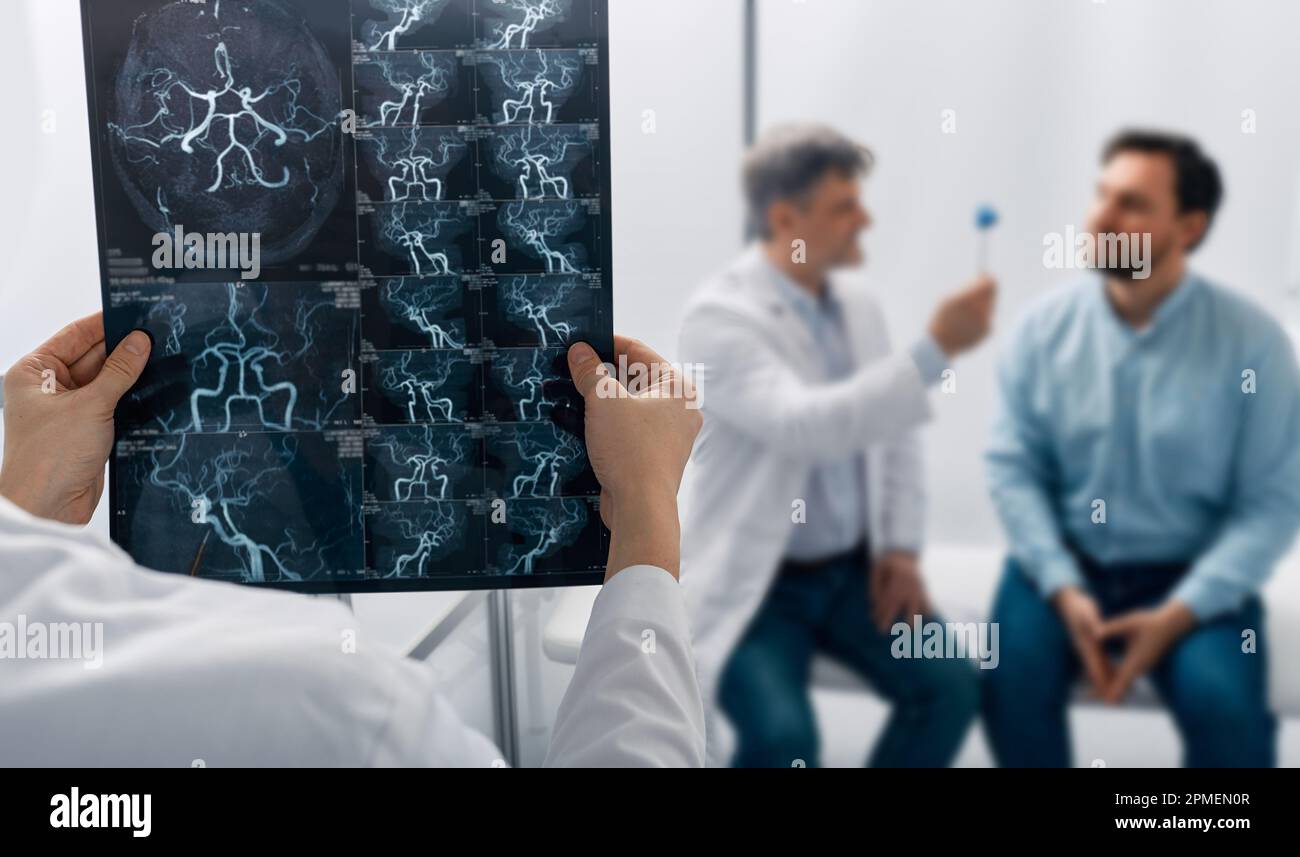Arzt Neurologe untersucht zerebrovaskuläres MRT-Bild des Gehirns während einer ärztlichen Konsultation bei Patienten mit Kopfschmerzen und Schwindel. MRA des Kopfes Stockfoto