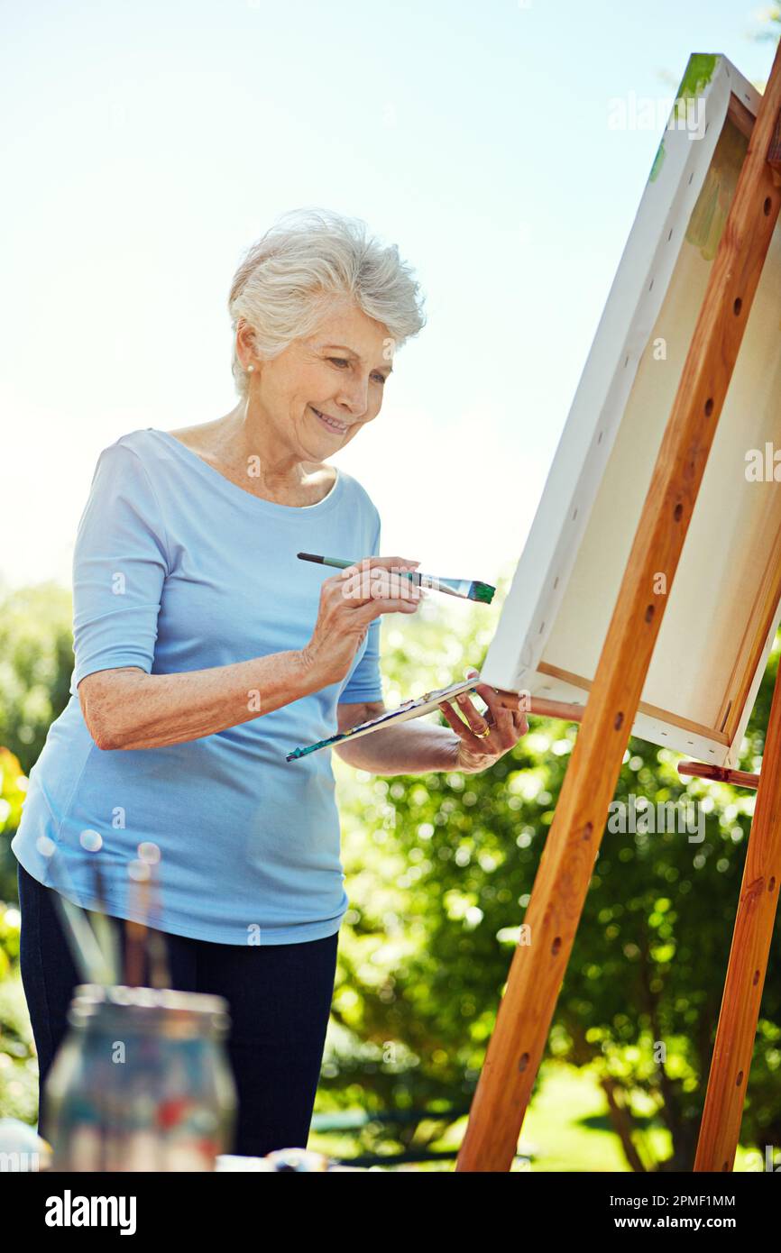 Die einzige Inspiration, die sie braucht, ist die Natur. Eine Seniorin, die im Park malt. Stockfoto