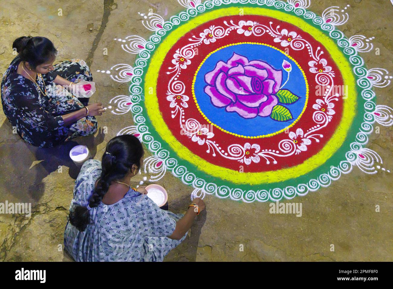 Indien, Karnataka, Hampi, das von der UNESCO zum Weltkulturerbe erklärt wurde, Frauen realisieren ein Rangoli oder kolam (Design mit Pulver) für das neue Jahr Stockfoto