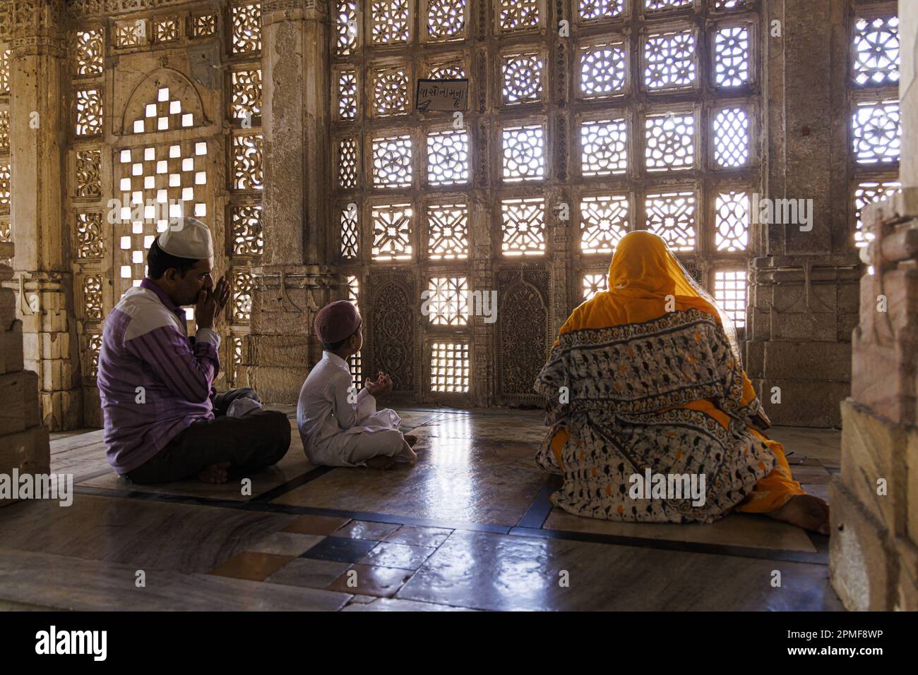 Indien, Gujarat, Ahmedabad, Sarkej Roza, Königskammer, Ein Paar und ein Kind beten vor einem Jali Stockfoto