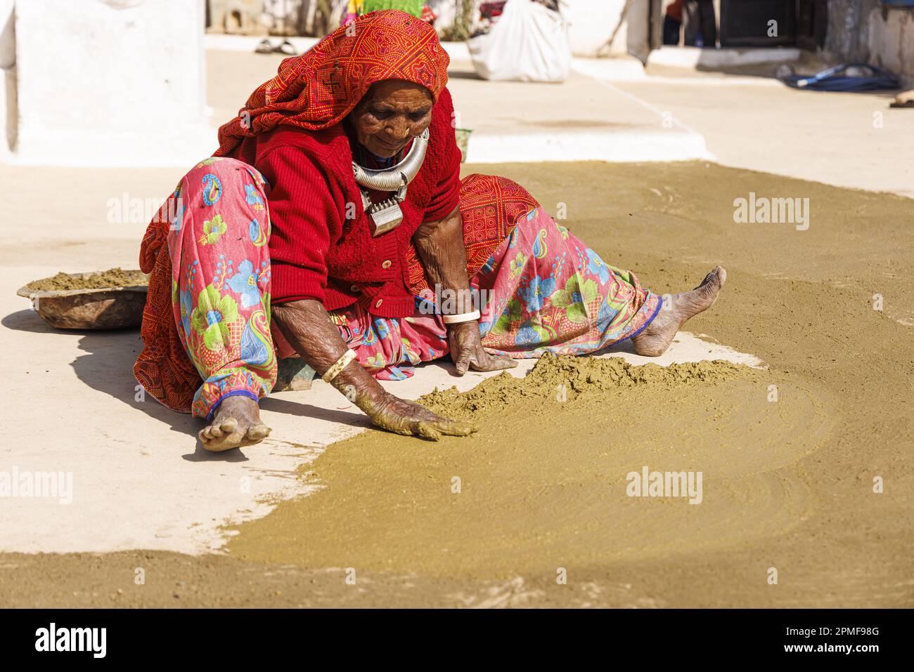 Indien, Gujarat, Bhujodi, Meghwal Woman erneuert den Boden eines Hauses mit einer Mischung aus Lehm und Kuhdung Stockfoto