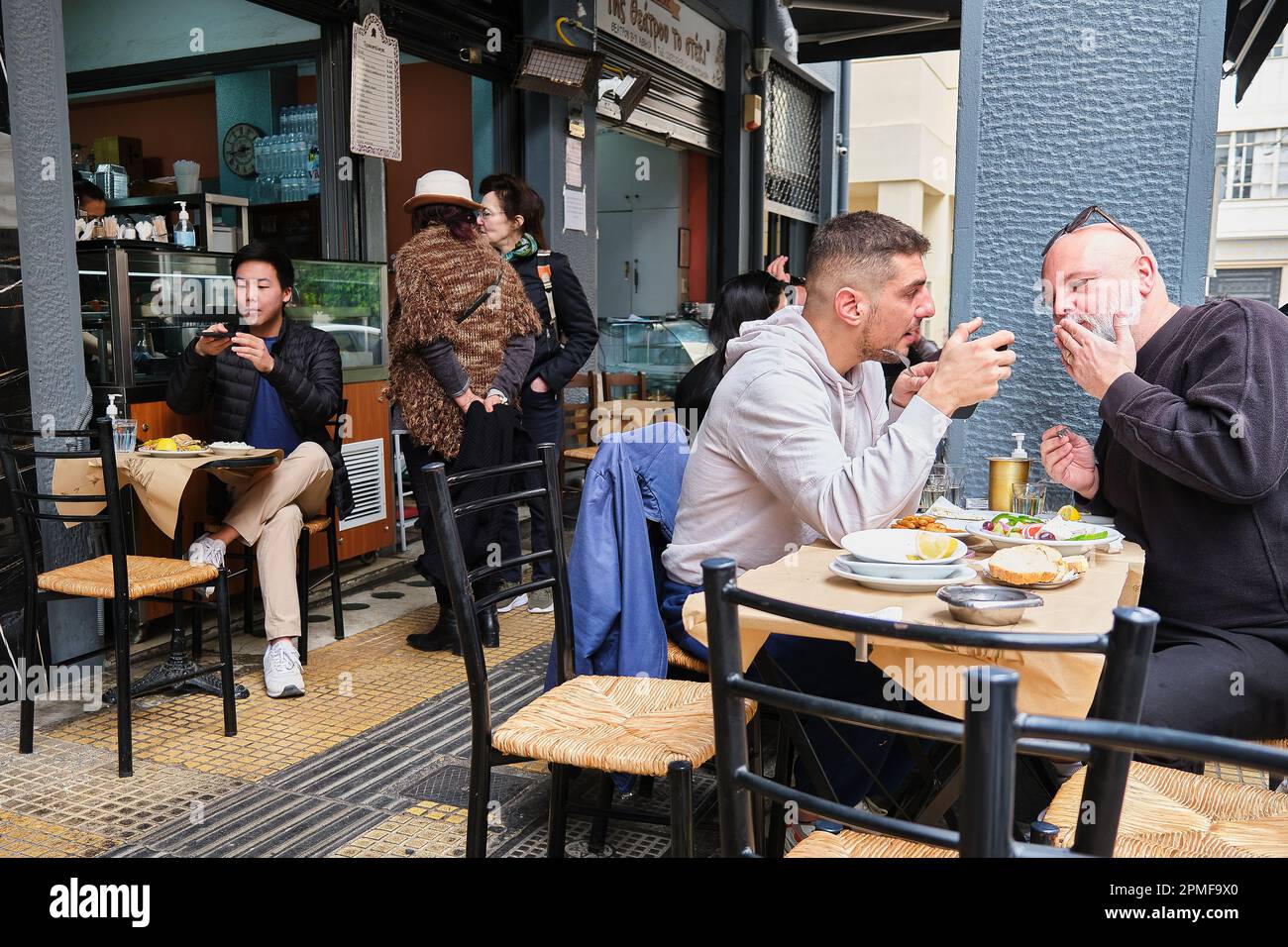 gäste spielen beim Mittagessen in Athen, Griechenland, mit ihrem Handy Stockfoto
