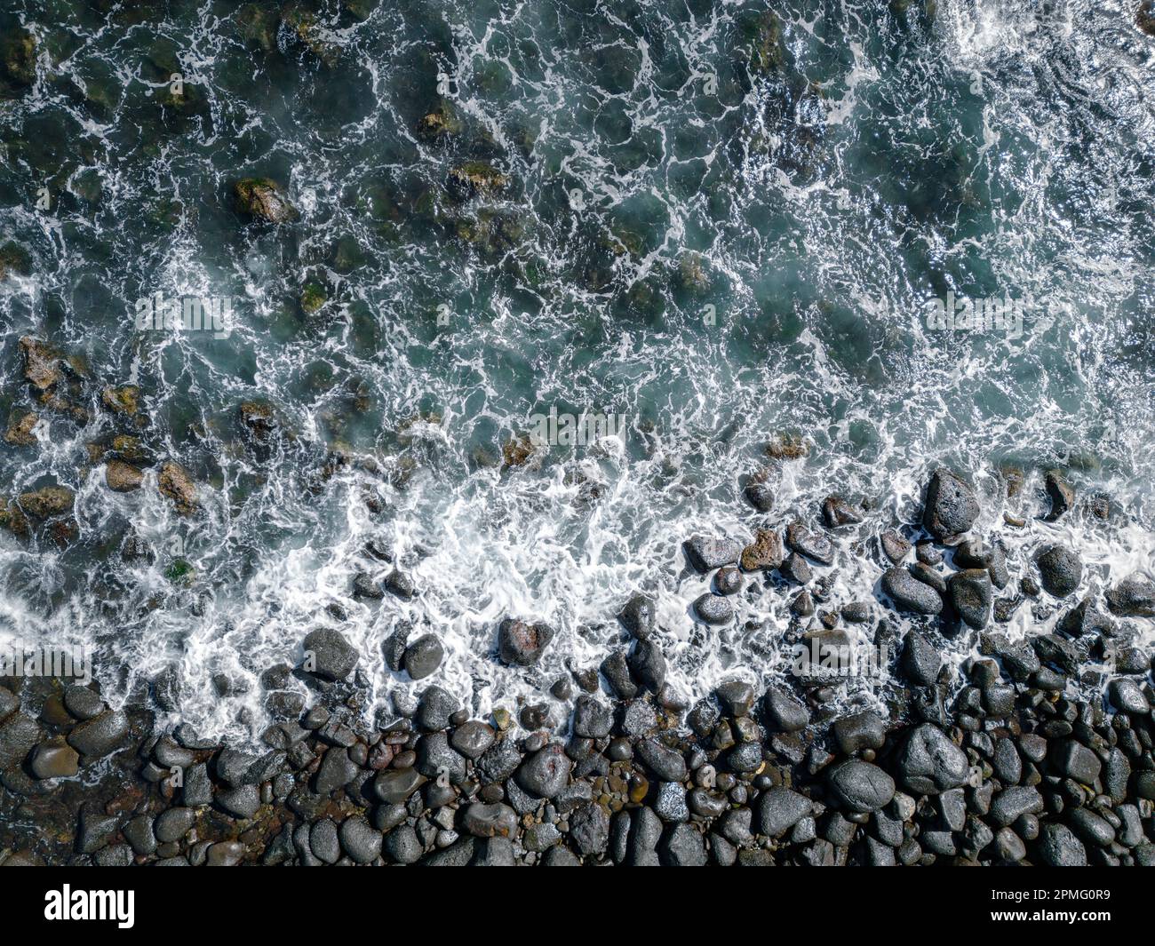 Luftaufnahme zu den Ozeanwellen. Blauer Hintergrund. Draufsicht auf das schäumende Wasser des Blauen Ozeans. Stockfoto