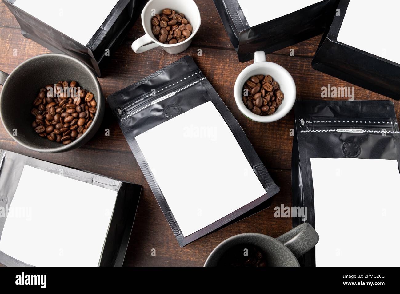 Schwarzer Verpackungsbeutel aus Kaffeefolie mit leerem weißem Etikett auf Holztisch Stockfoto