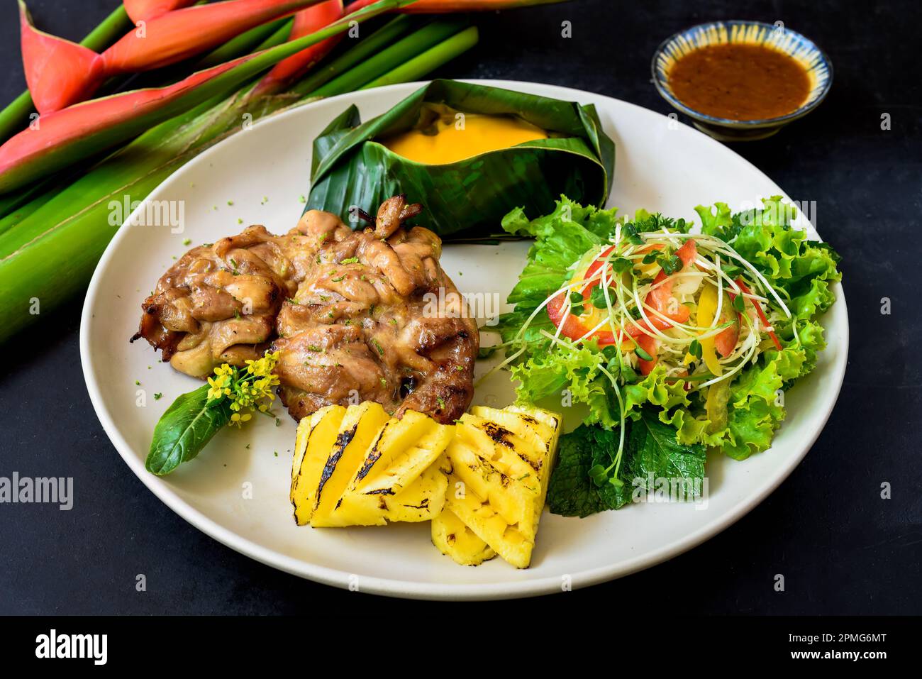 Vietnamesisches Hühnchen mit entbeinten Beinen mit Babymais unter Käse, Salat und gegrillter Ananas Stockfoto
