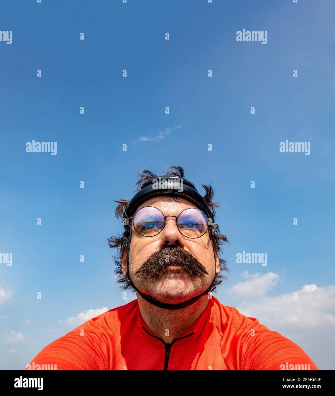 Ein Radfahrer fährt auf einem Fahrrad in einem Retro-Helm unter einem blauen Himmel Stockfoto