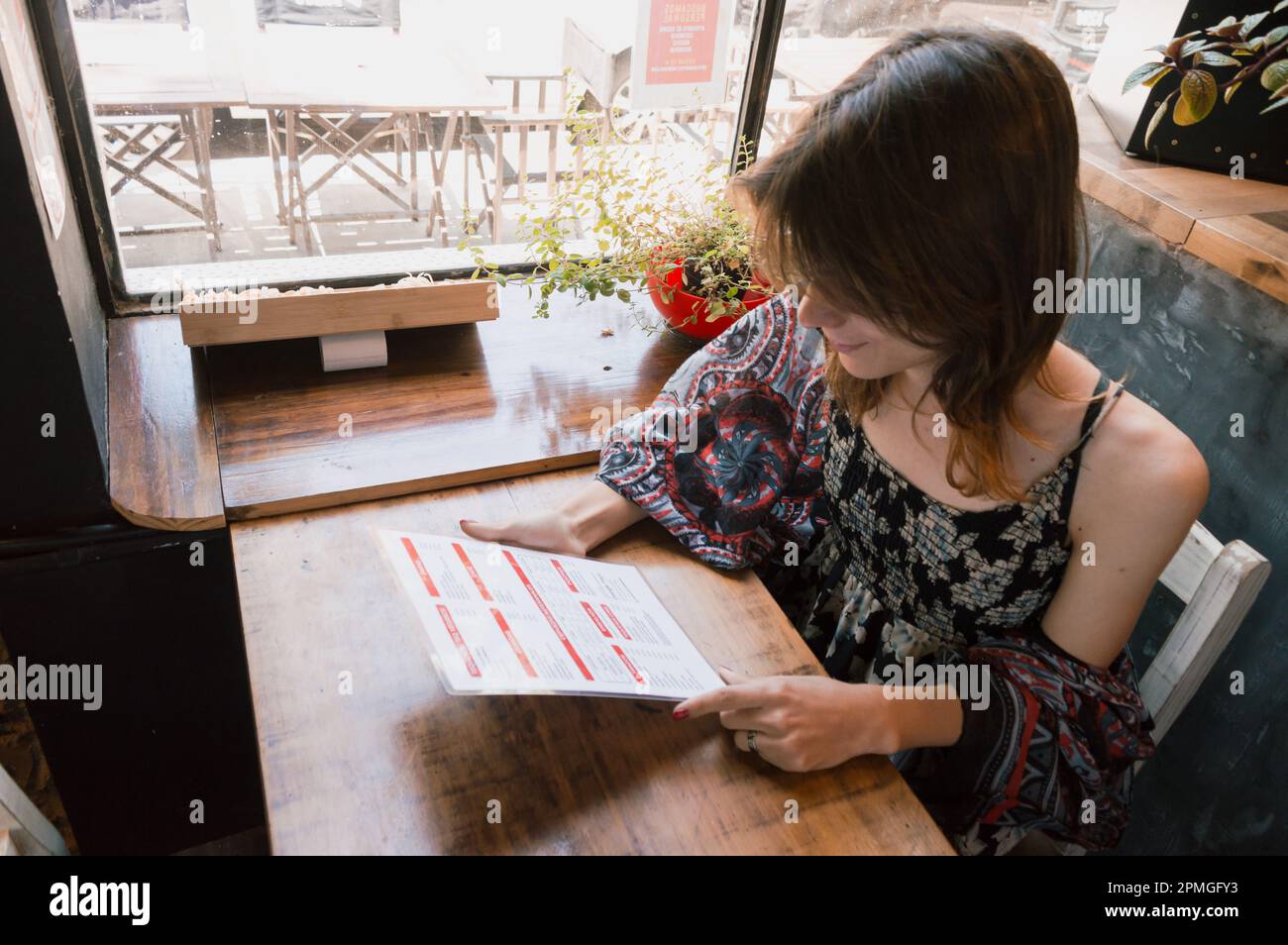 transsexuelle argentinische ethnische Zugehörigkeit junge lateinische Frau, die im Restaurant Entscheidungen trifft, die Speisekarte liest, am Tisch sitzt, Geschäftskonzept, Kopierbereich. Stockfoto